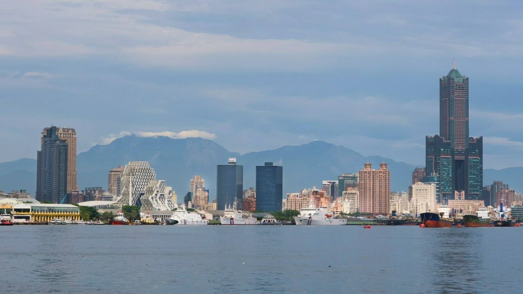 Downtown Kaohsiung. Various buildings with different architecture line shore. In the background are mountains