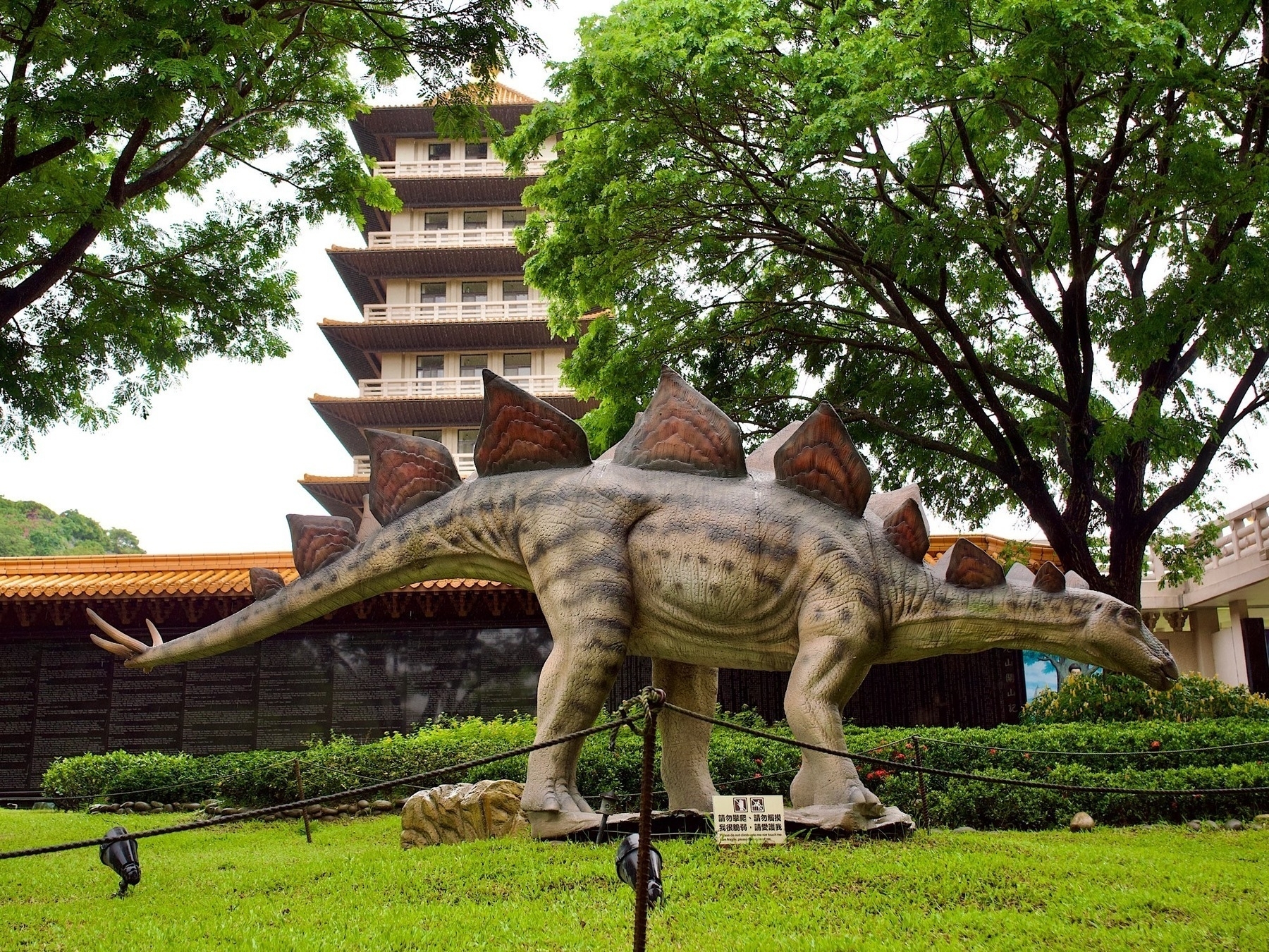 A stegasaurus statue in front of a Buddhist pagoda