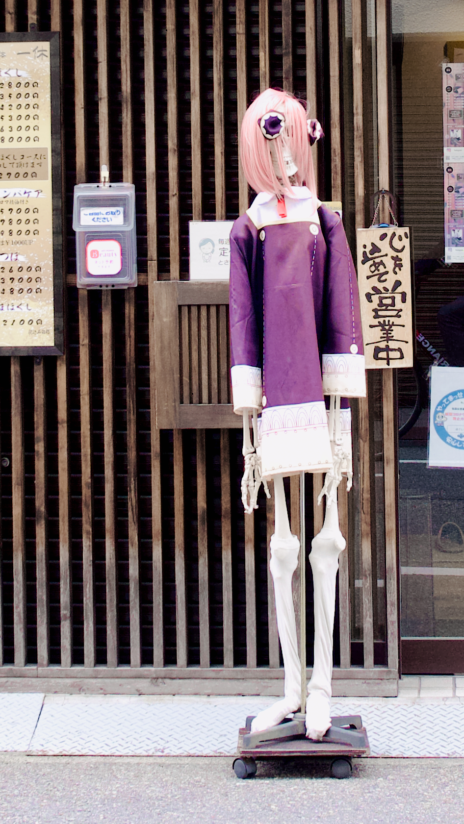 A life-sized medical human skeleton model stands in front of a shop cosplaying as Anya from Spy Family… ?