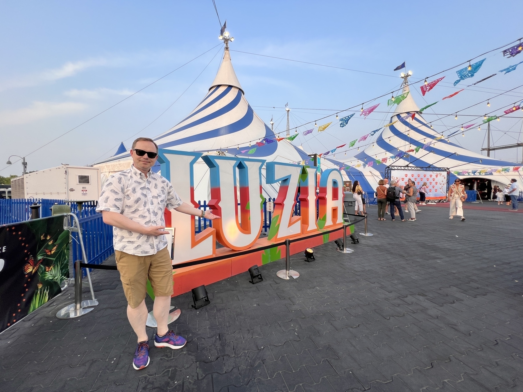 Chad standing outside some circus tents with a signed saying LUZIA