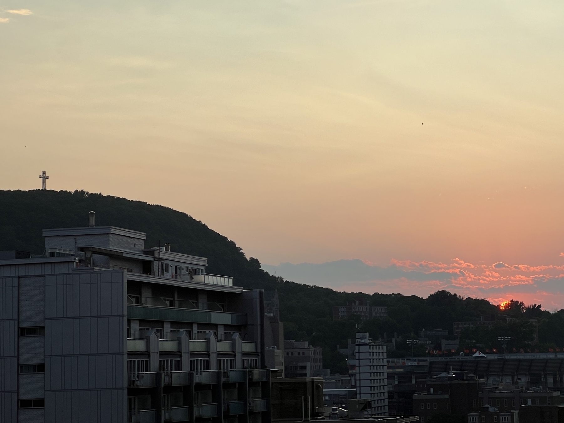 Sun sets behind the horizon as the cross of Mount Royal looks down on the city