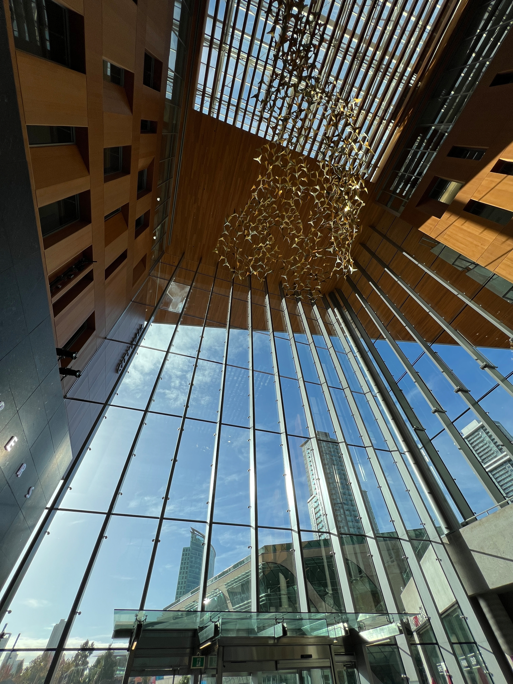 Inside Surrey City hall with its huge 5 story glass entrance and gold bird flock susurration art installation on the ceiling 