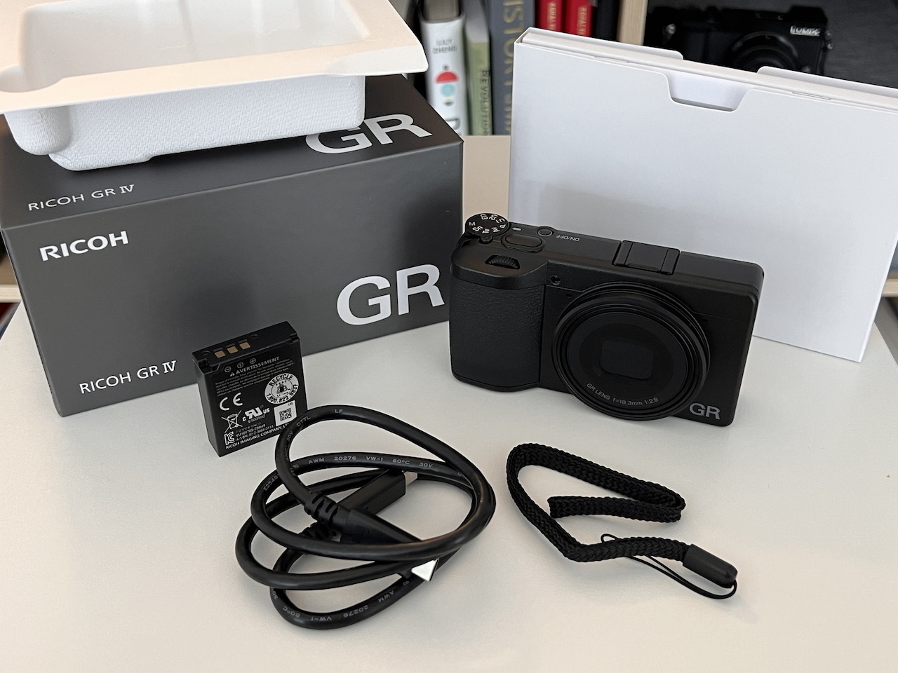All the contents from the Ricoh GRIV box out: camera, battery, wrist strap, and charging USB-C cable