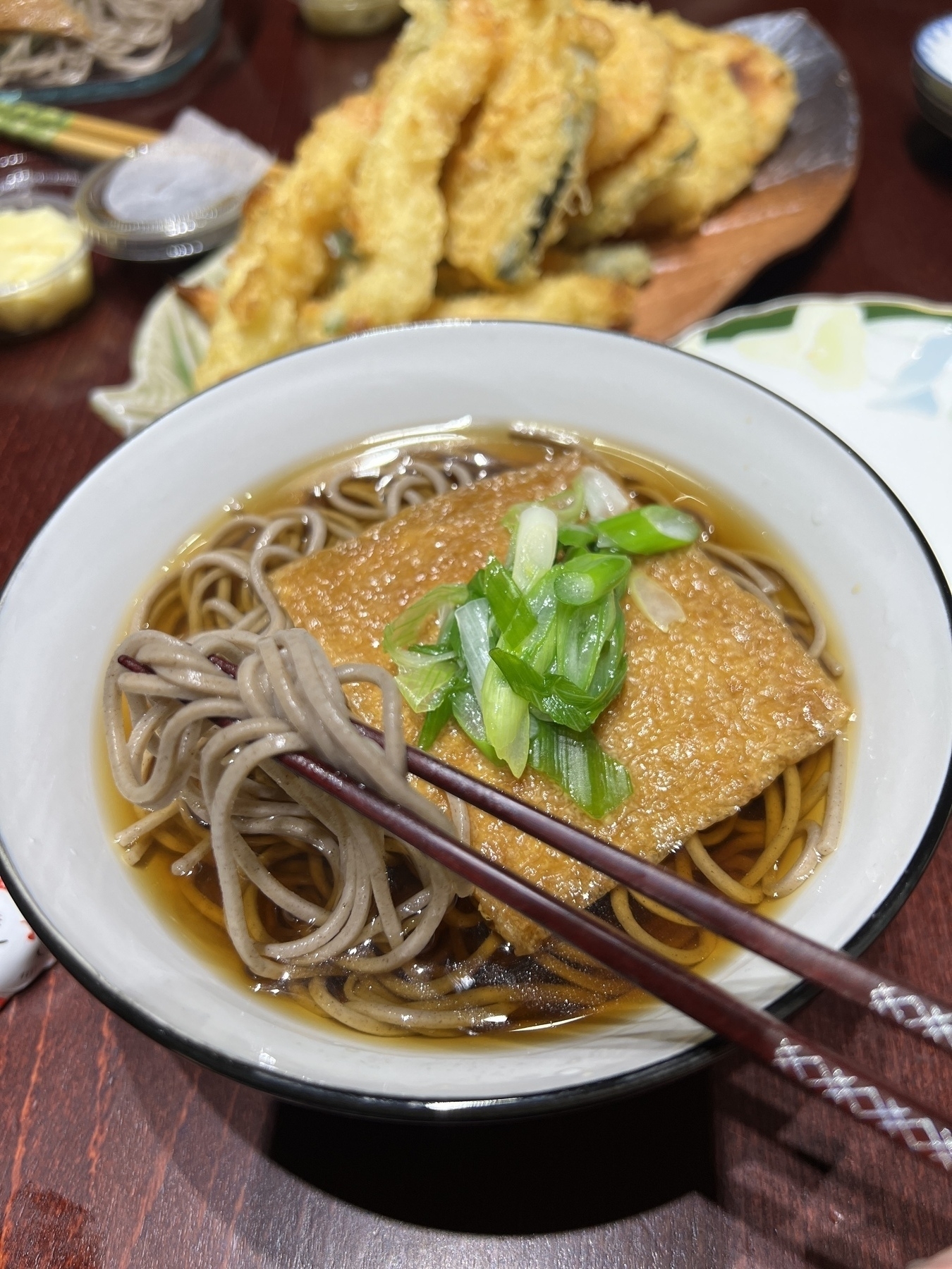 Bowl of kitsune so a with tempura in the background