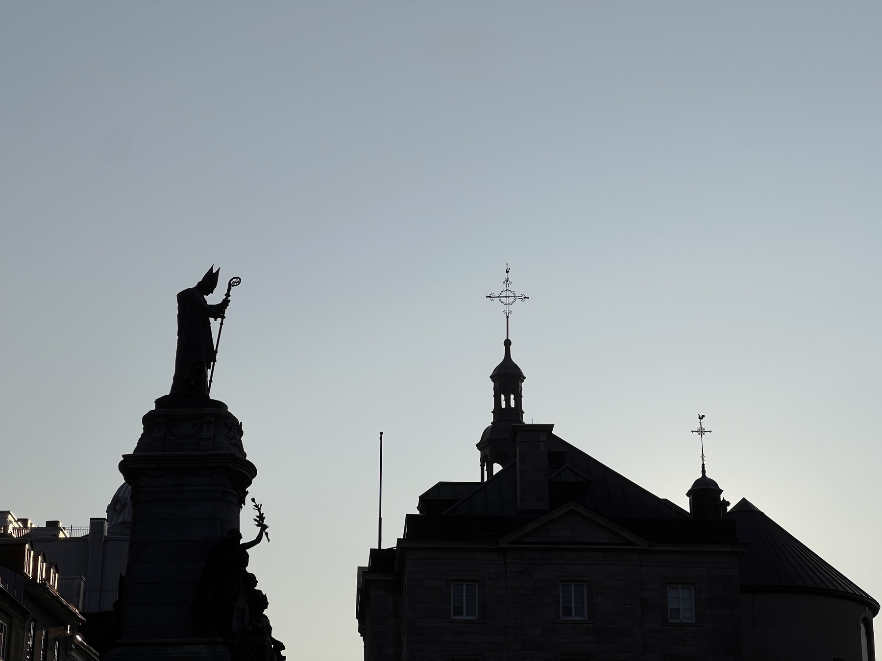 Saint François de Laval Monument with the steeple crosses of Notre-Dame de Québec Basilica-Cathedral all in silhouette