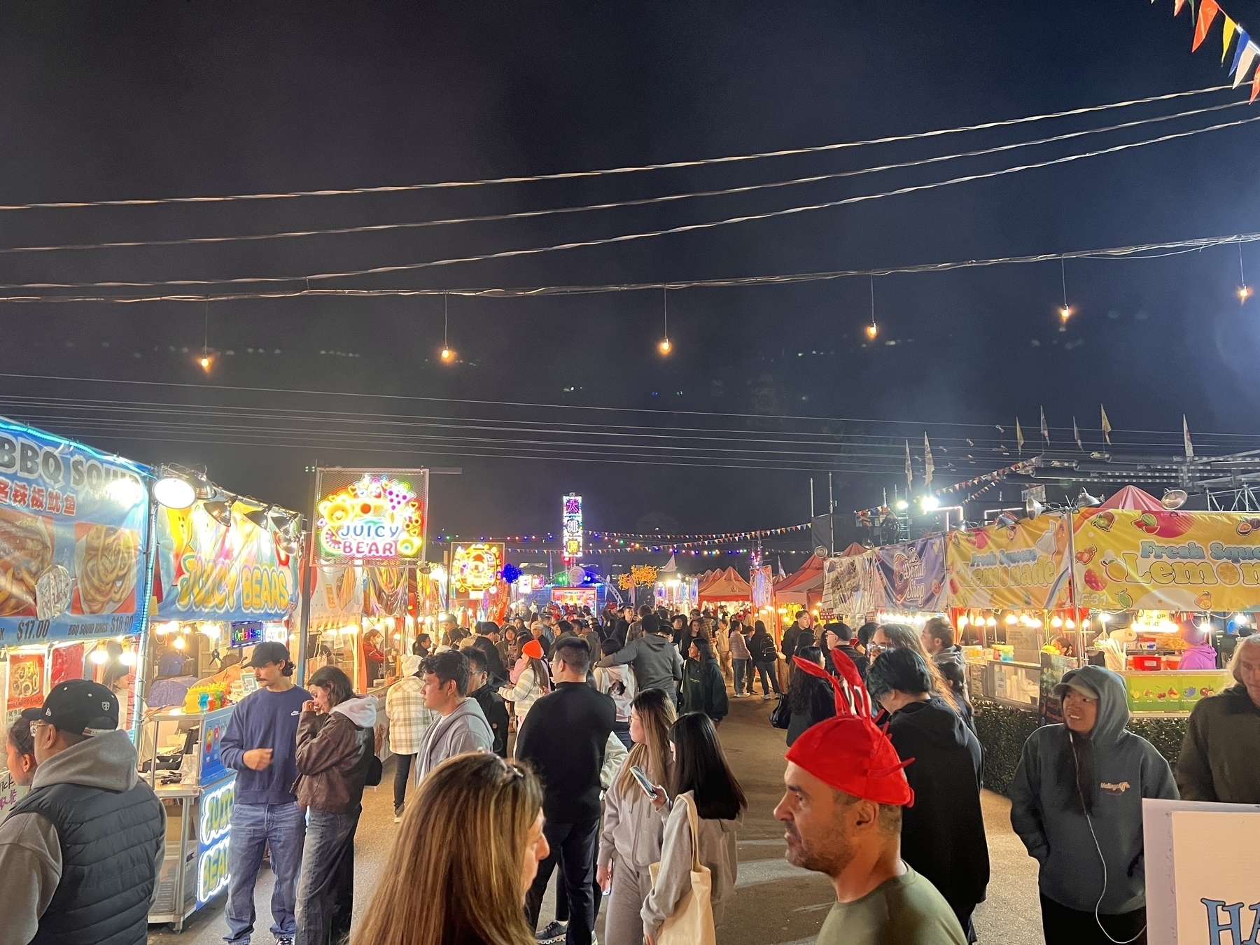 A busy night market with many people and food booths 