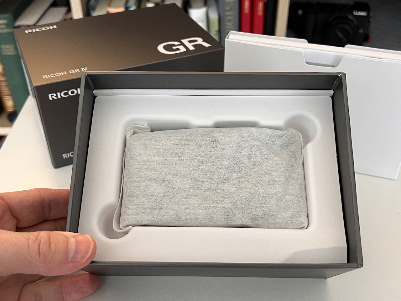 Opened box with Ricoh GRIV camera in a little protective baggie