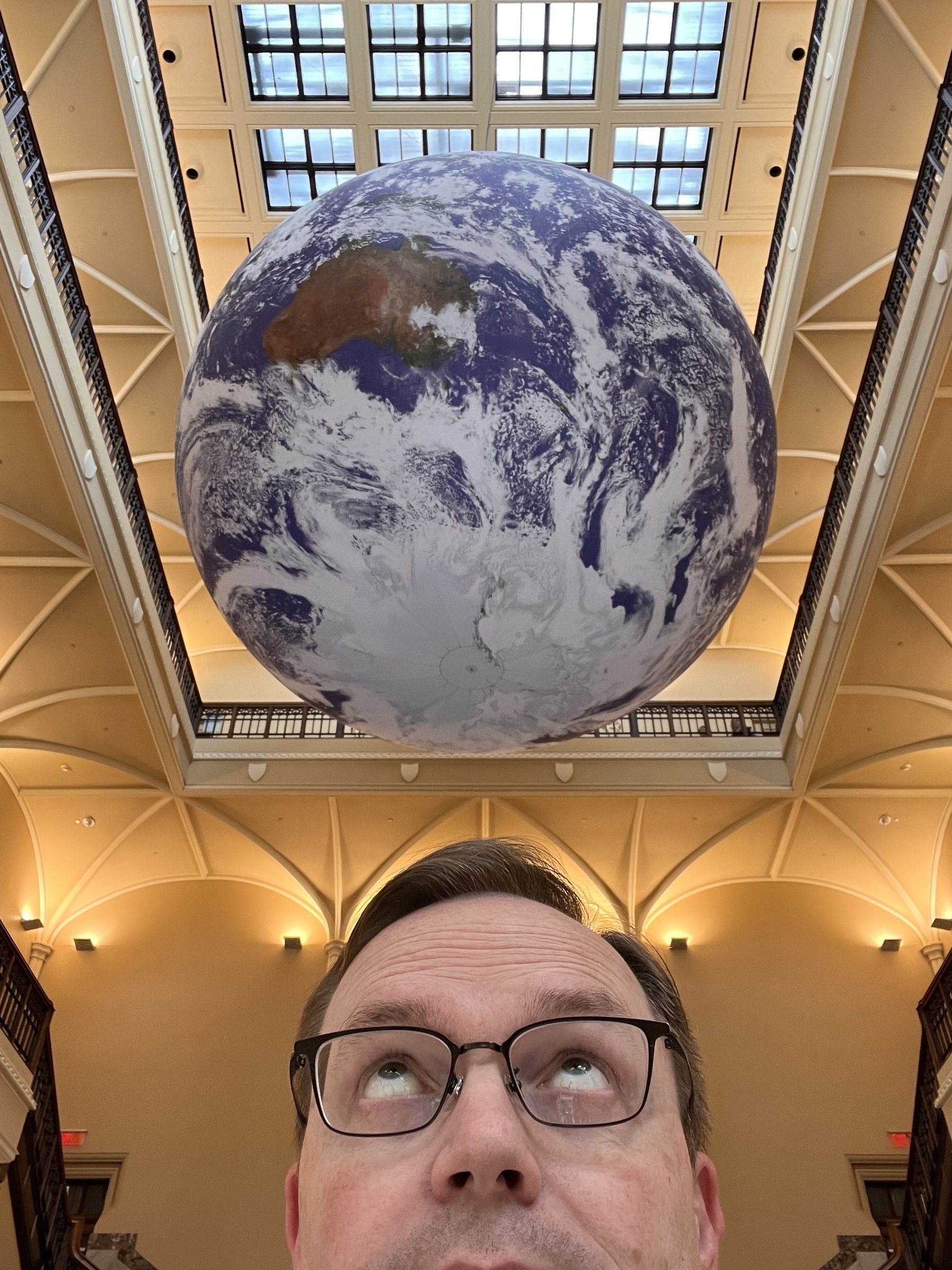 Chad selfie looking up at a giant model of the Earth