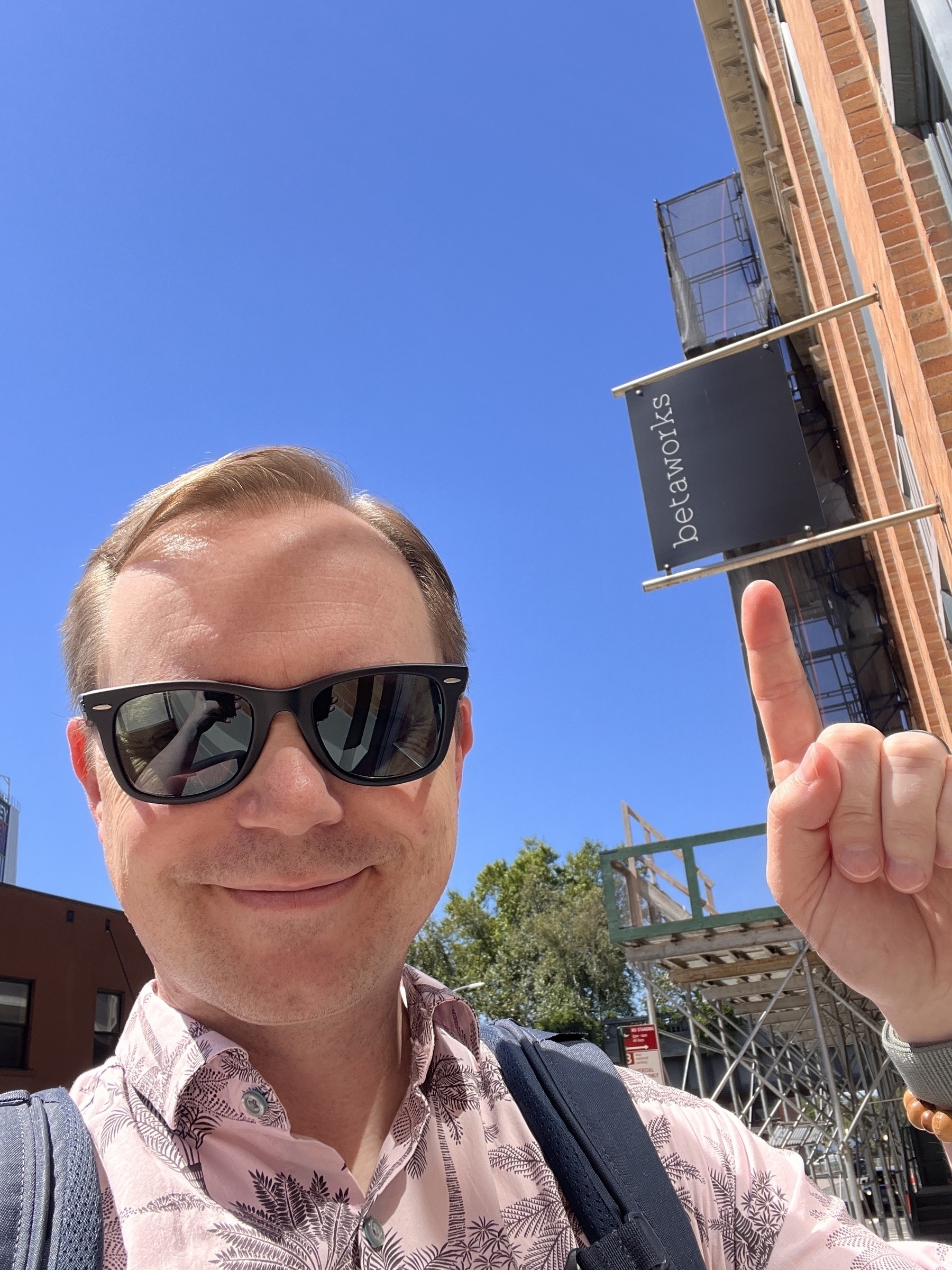 Chad selfie pointing at the Betaworks sign on a bright clear day