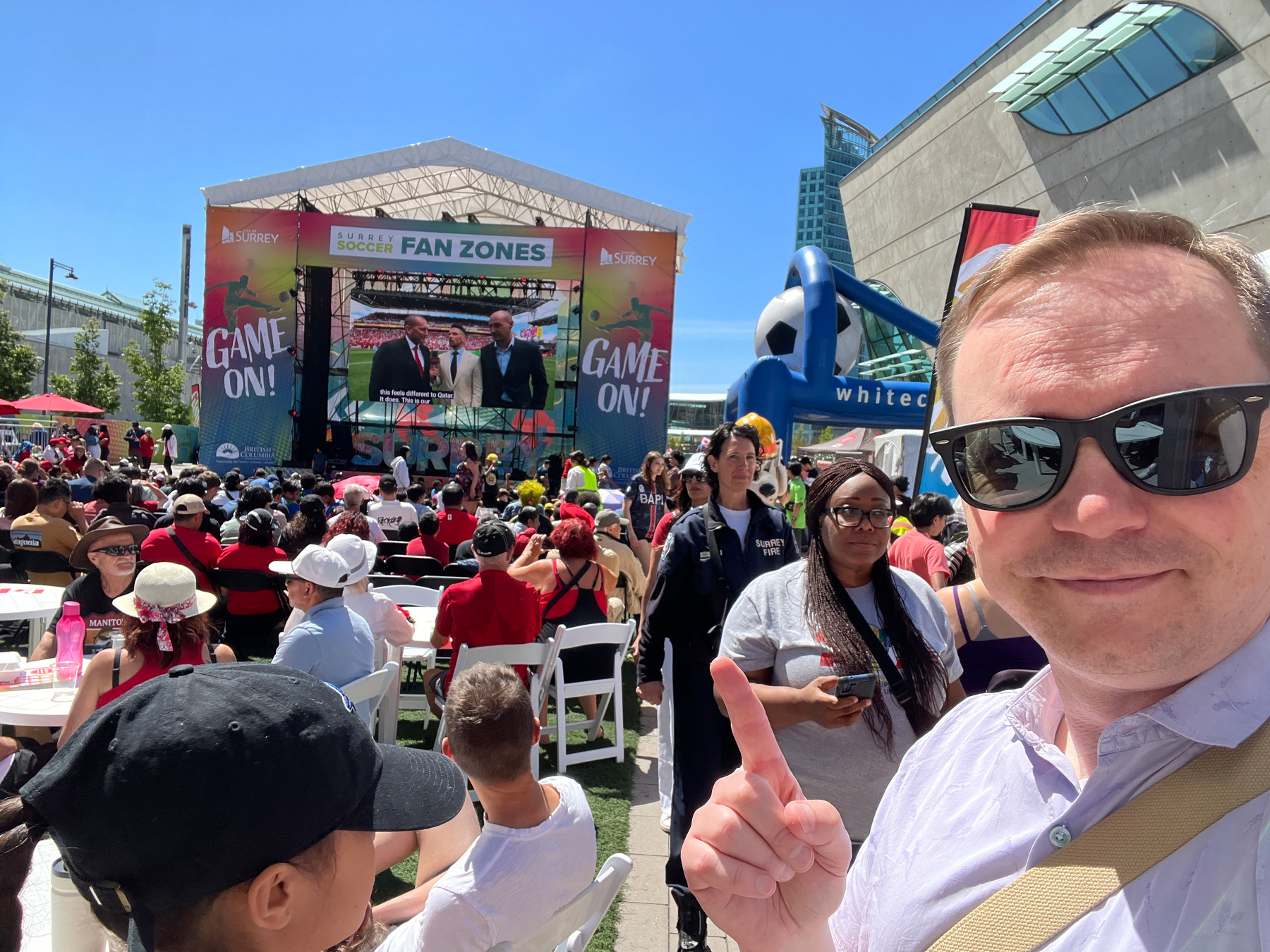Chad selfie pointing to a big screen surrounded by a ton of fans 