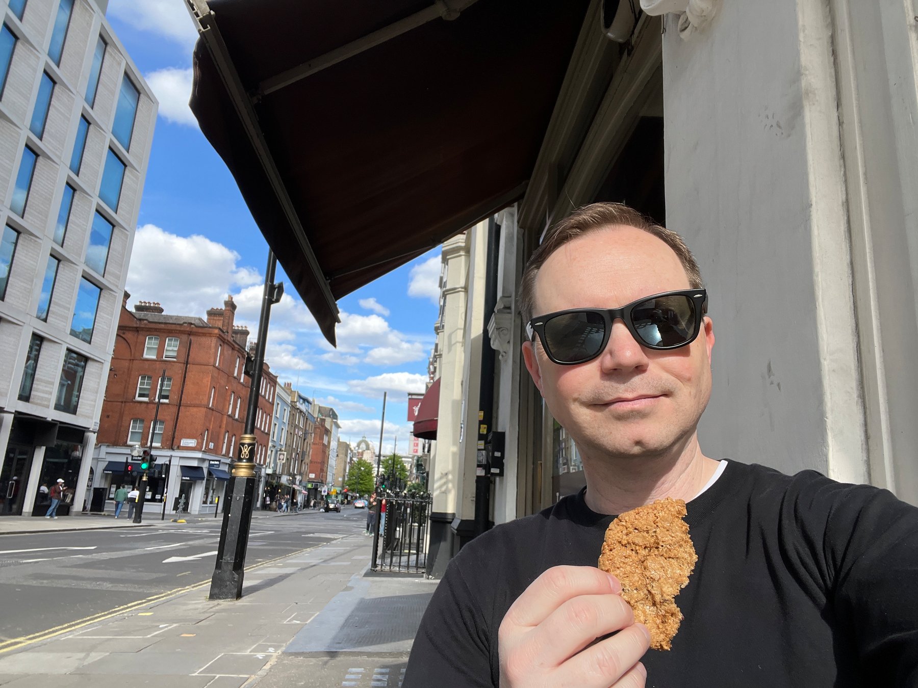 Chad brandished a cookie on a sunny street wearing sunglasses