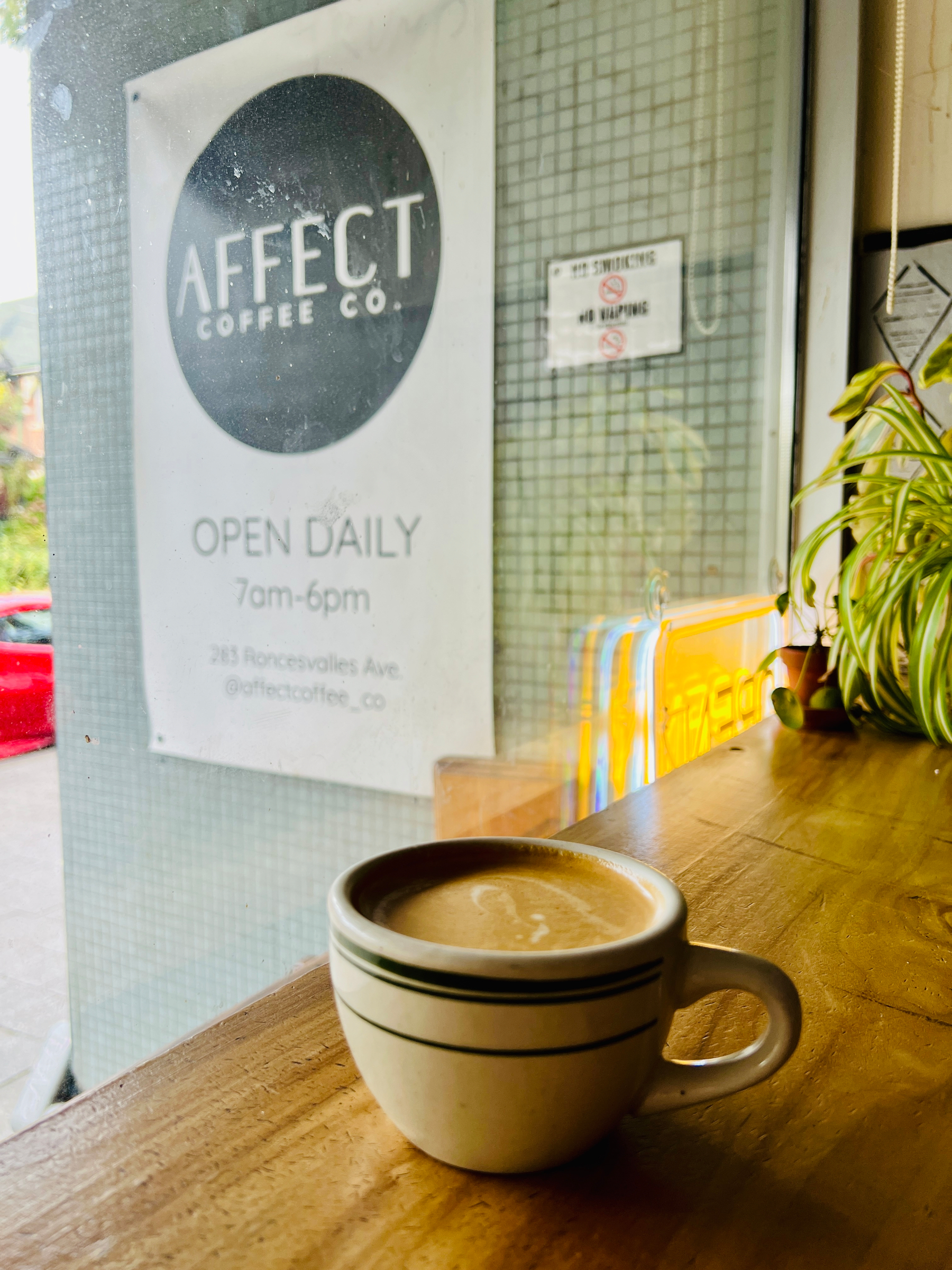 Flat white on a window counter. Outside is the sign for Affect Coffee co