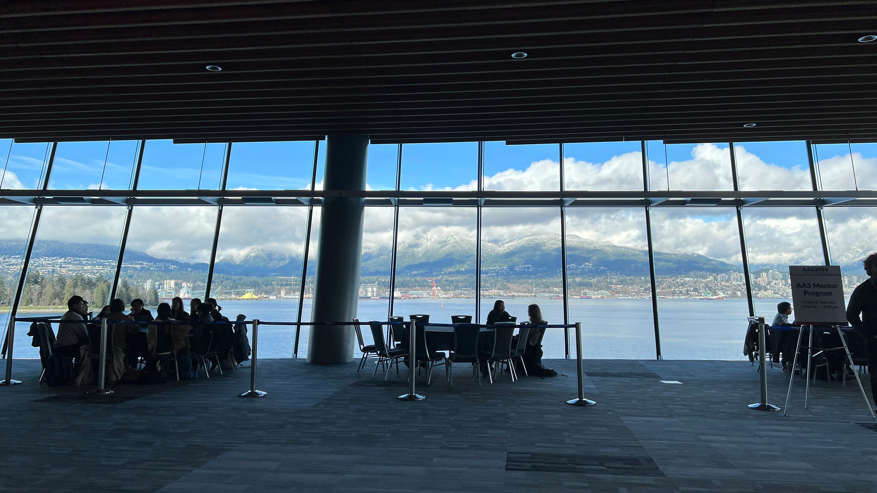 Silhouette's of People at conference tables backed by windows overlooking the ocean with the North Shore in the distance