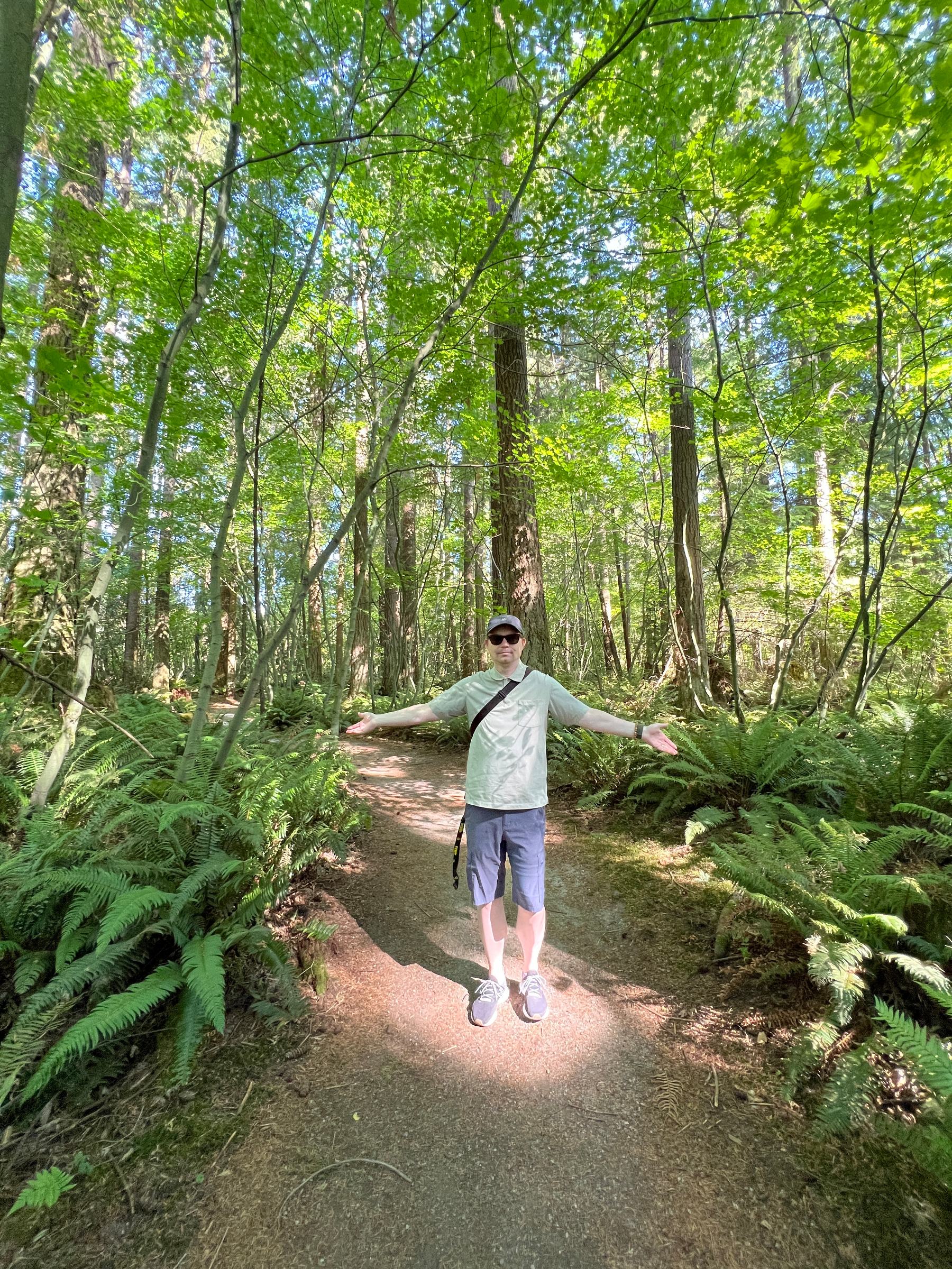 Chad stands surrounded by trees on a nature trail