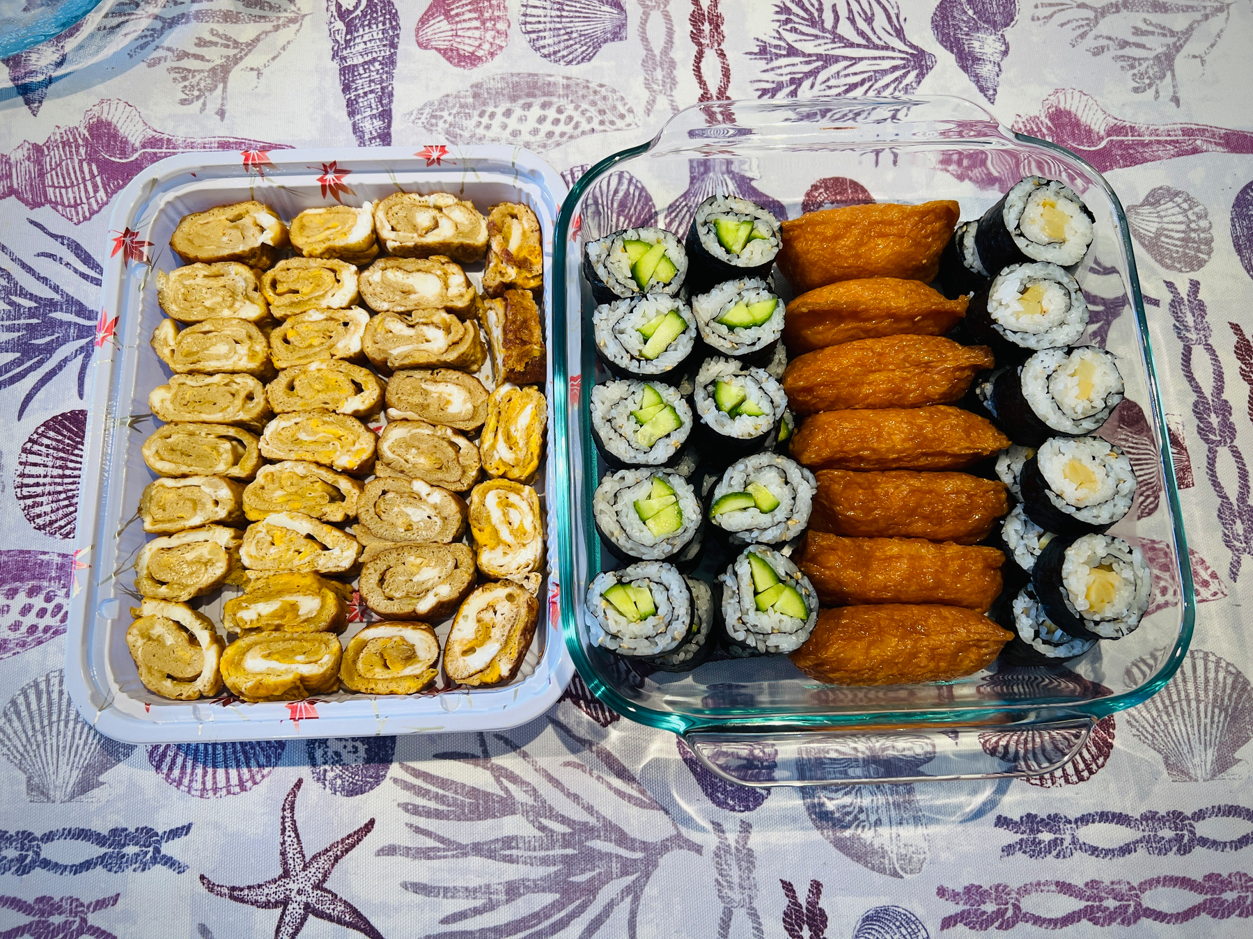Dashimaki tamago, kappa maki, oshinko maki, and oinari arranged in two containers 