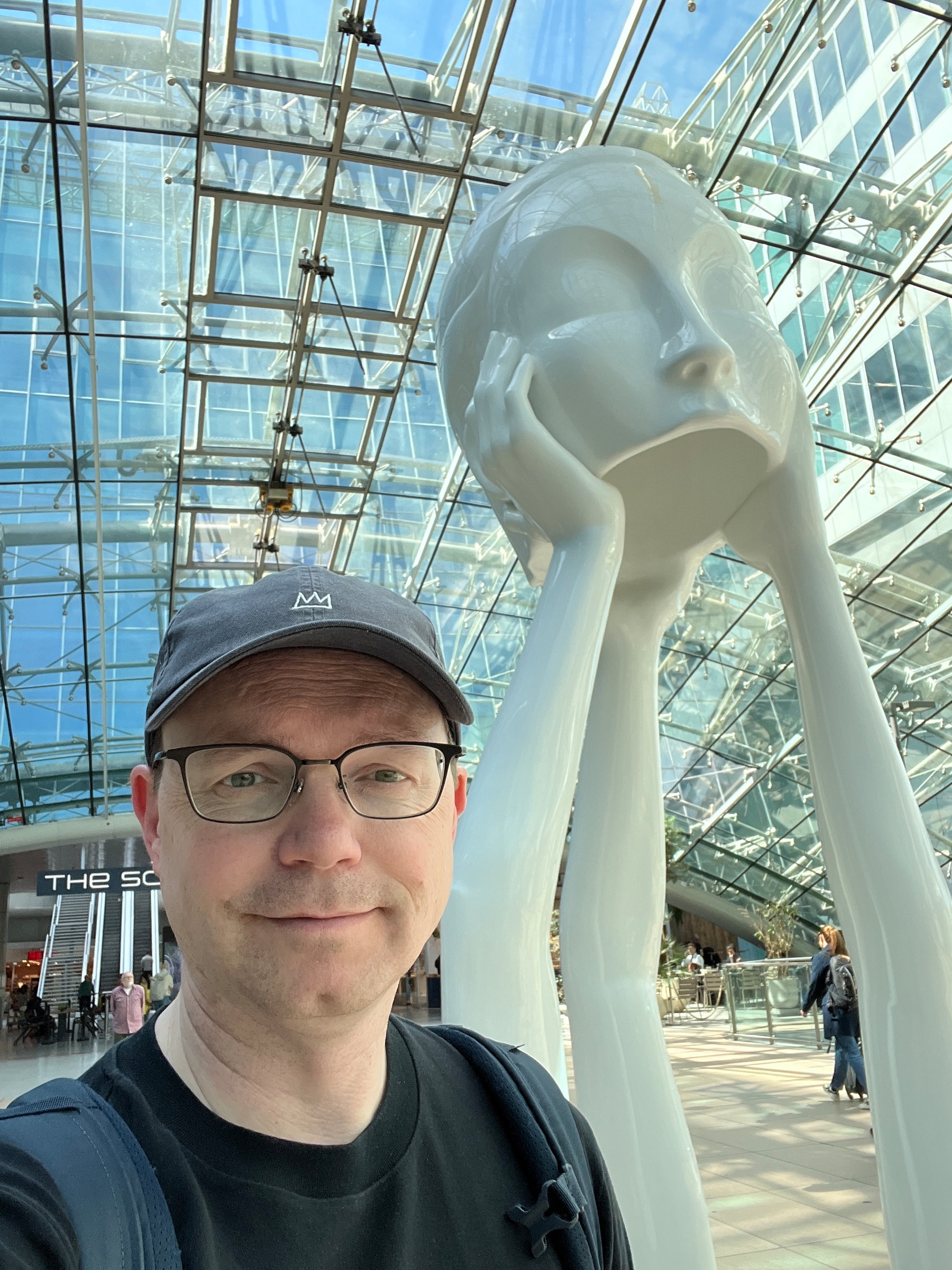 Chad in front of a statue of three arms holding up a head