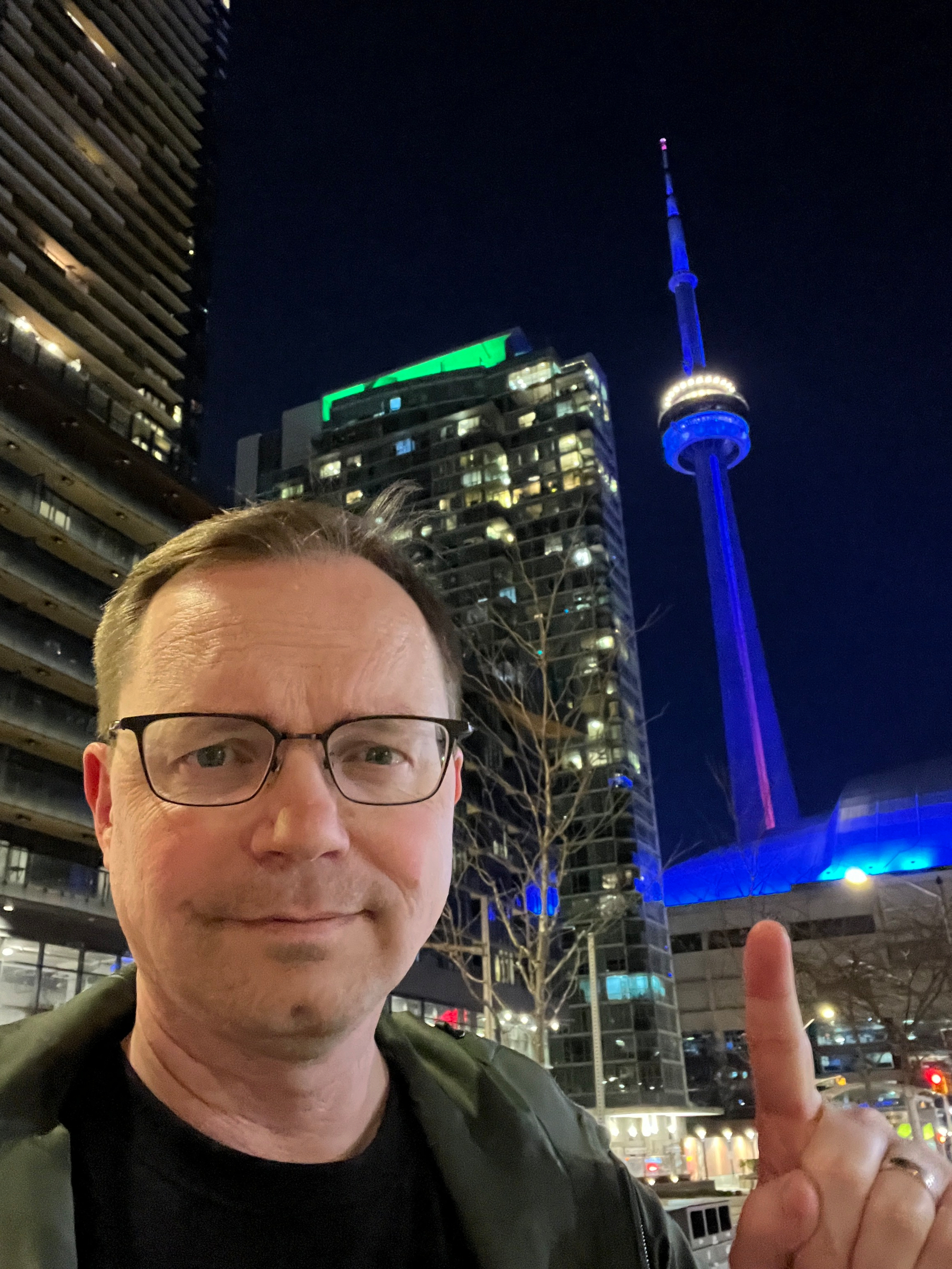 Chad points at the CN tower lit up blue at night