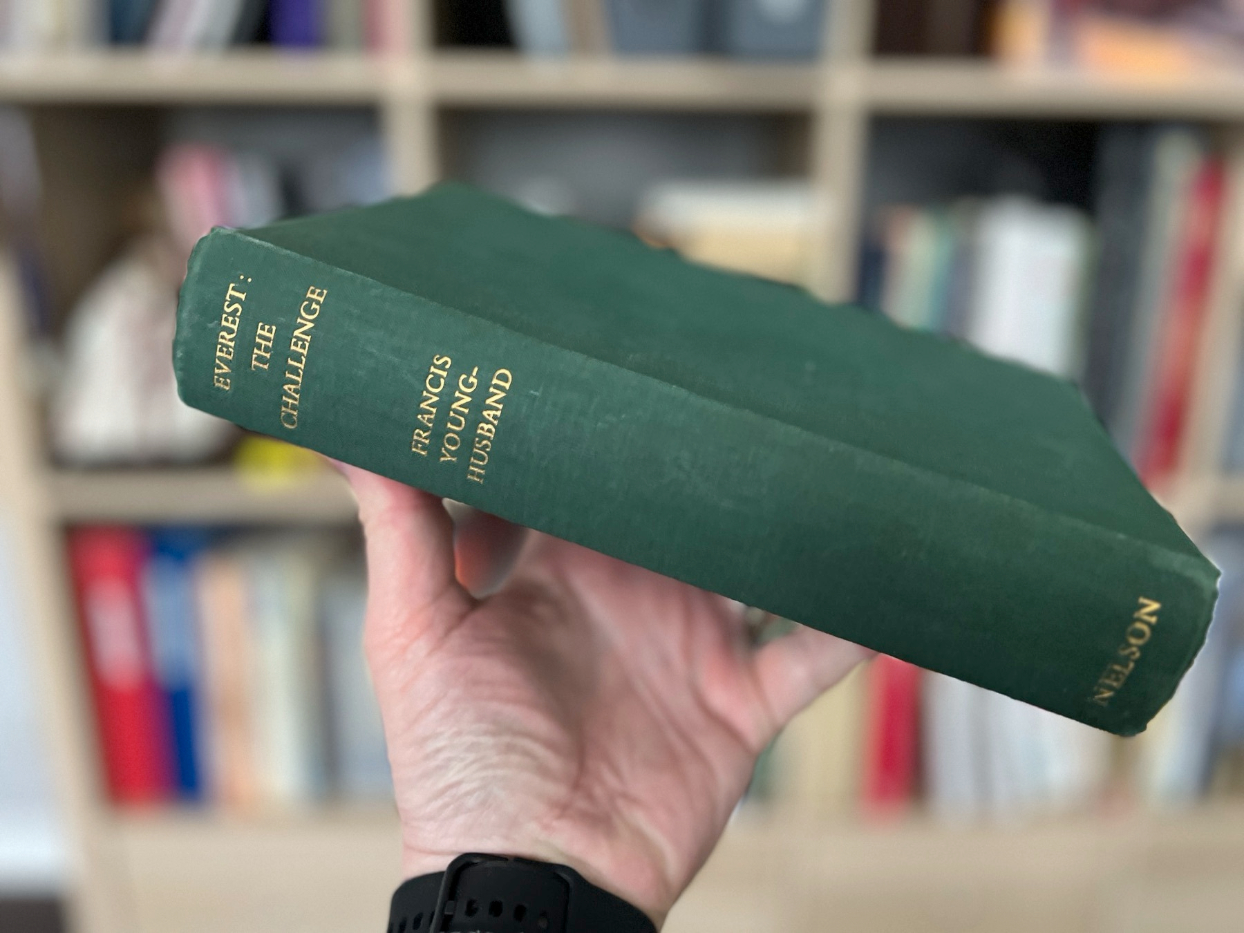 Chad holds Younghusband's Everest book up in front of his bookshelf