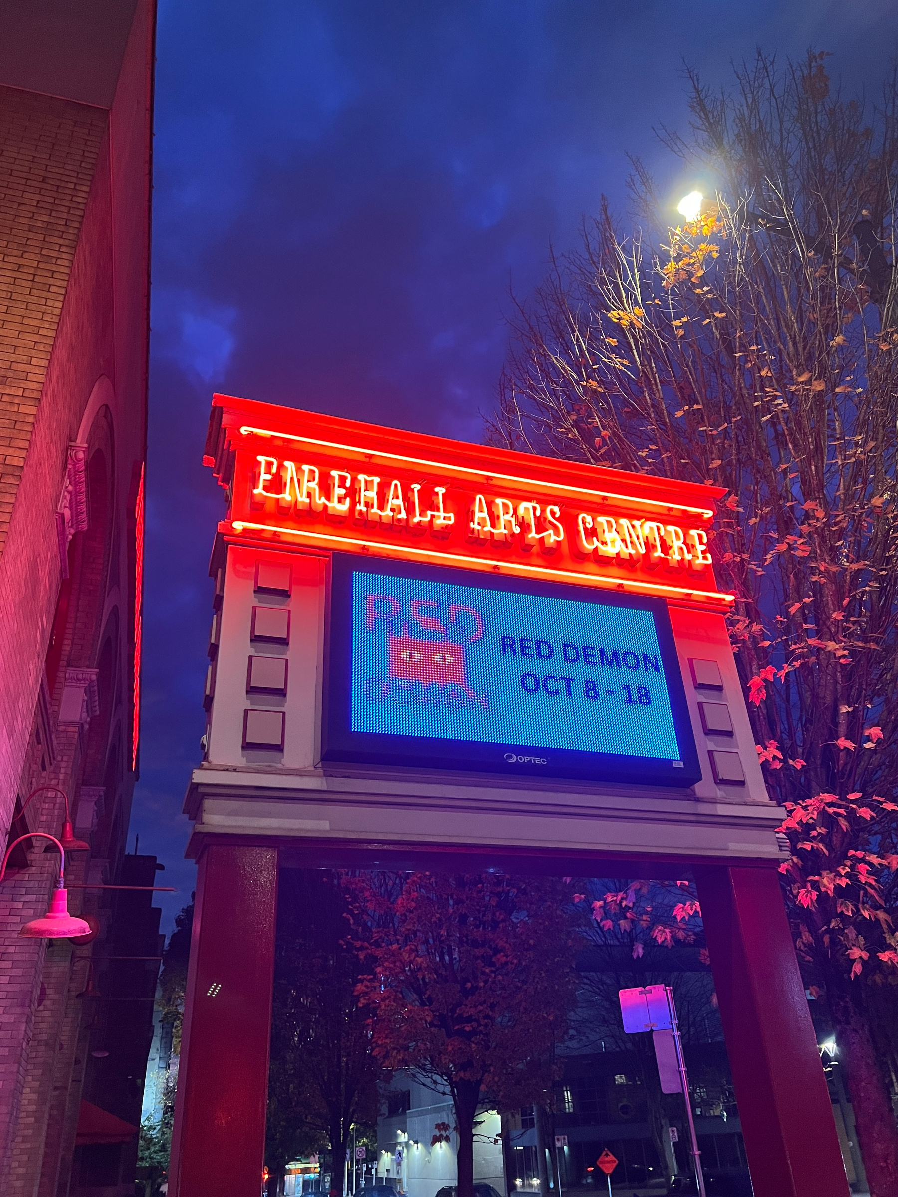 A brightly lit signboard for the Firehall Arts Centre announces the upcoming event Red Demon from October 8 to 18.