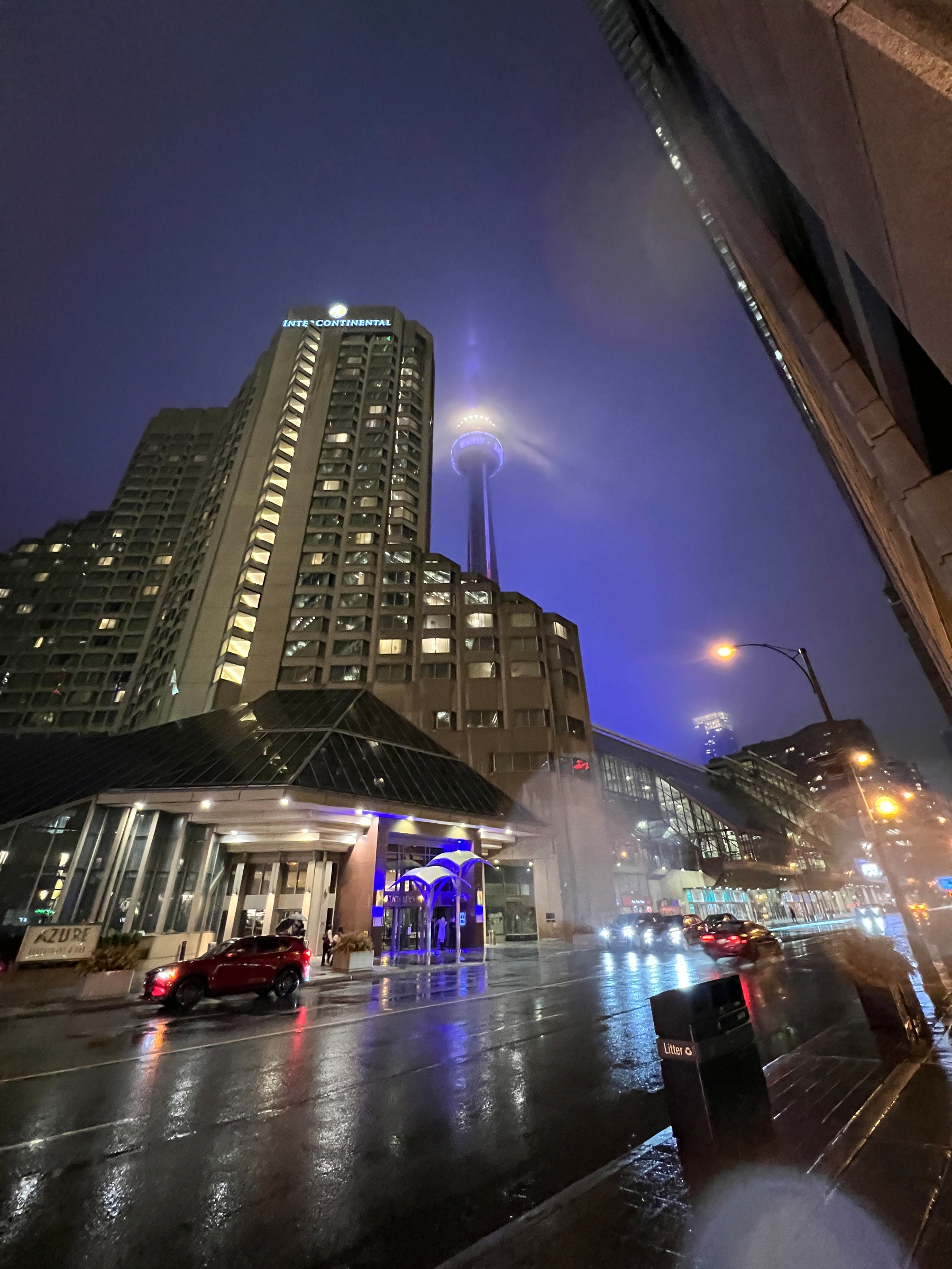 At night the Intercontinental Hotel with the CN Tower behind it, casting light into the fog