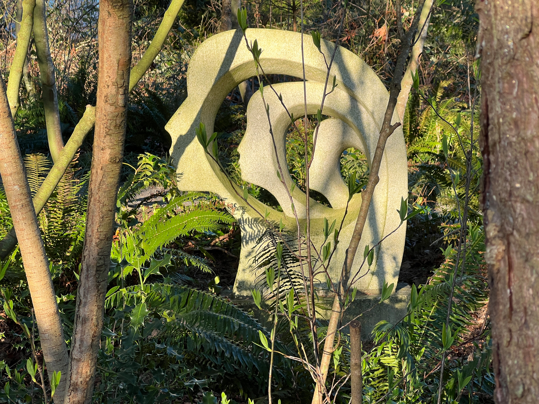 Sculpture of three faces through the trees