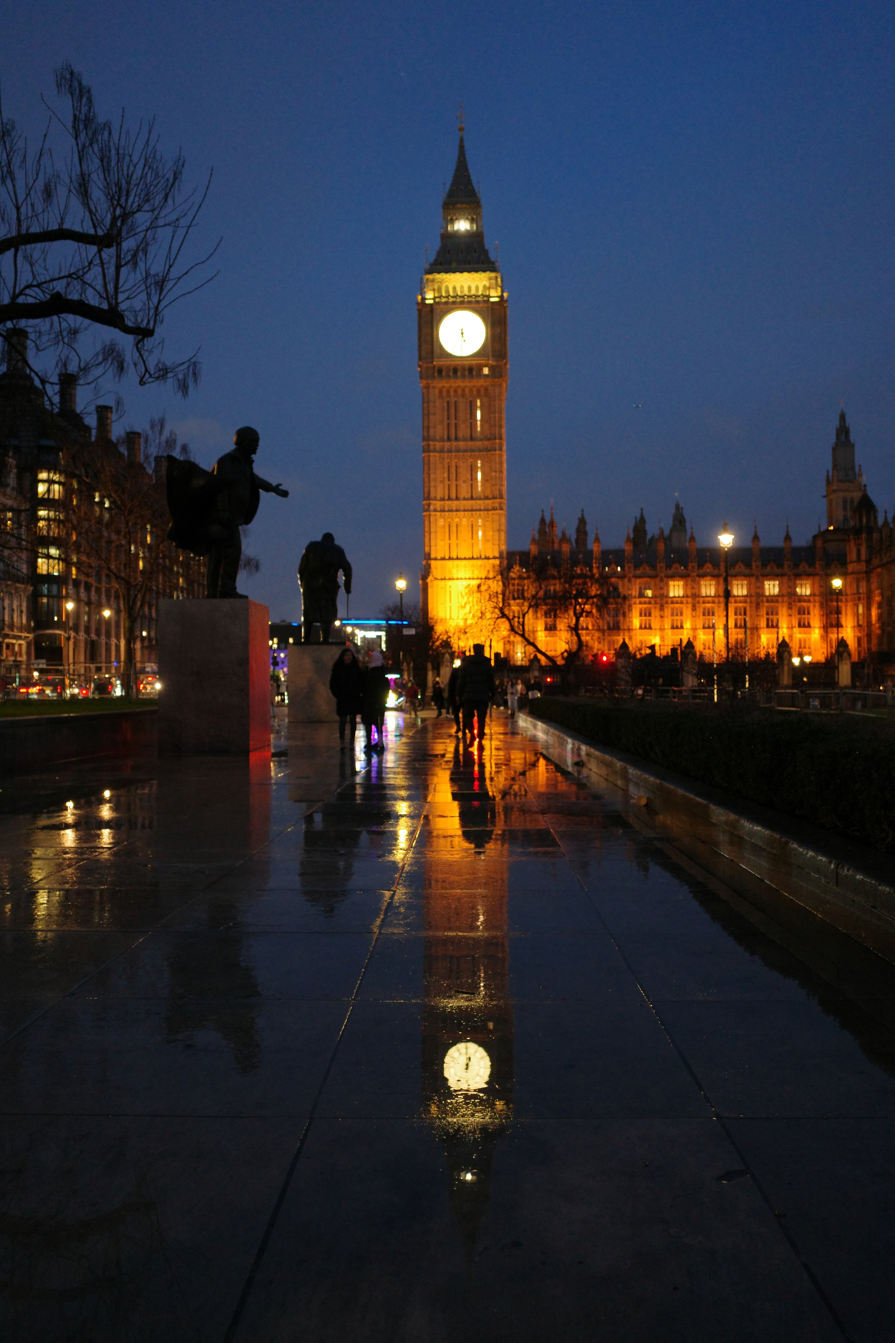 Big Ben reflects off of the rainy flagstones at night