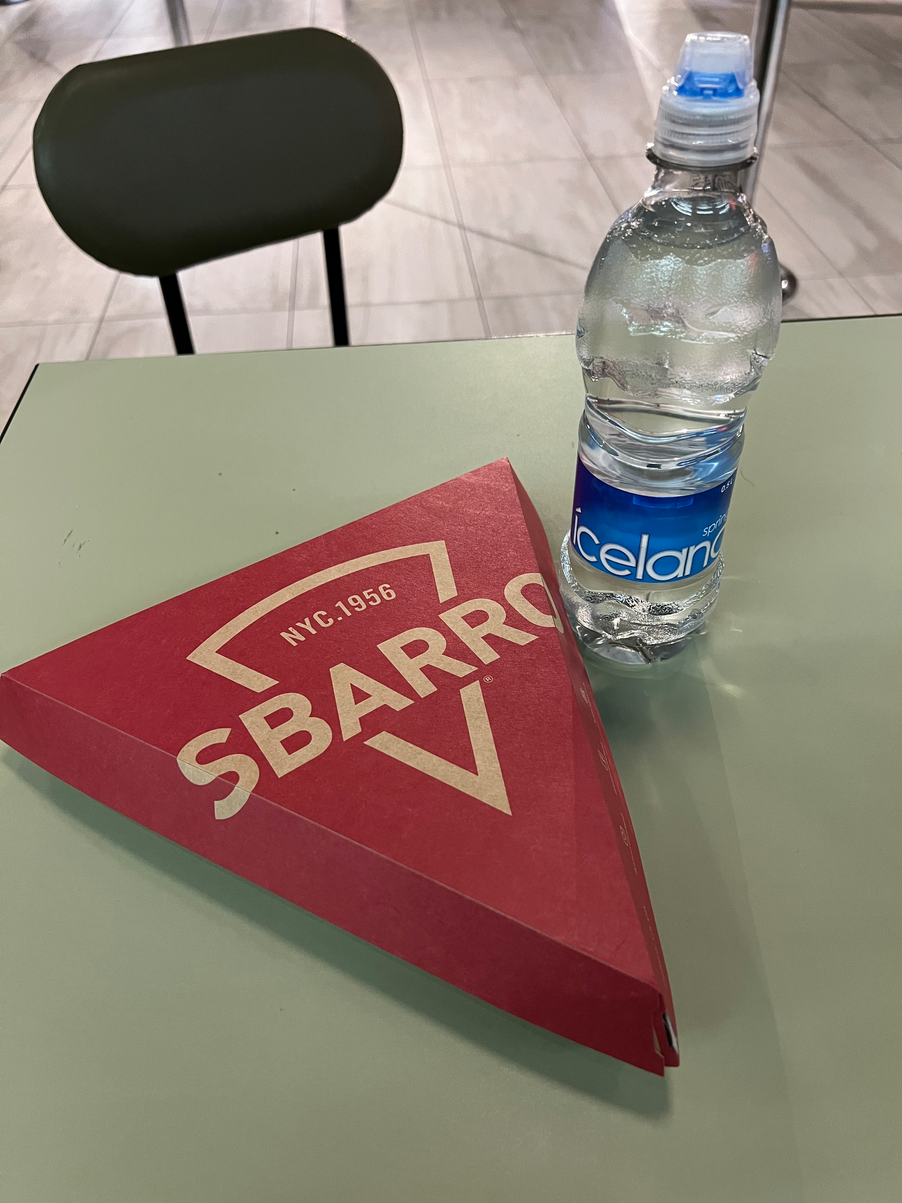 A Sbarro pizza slice box and bottle of Icelandic water