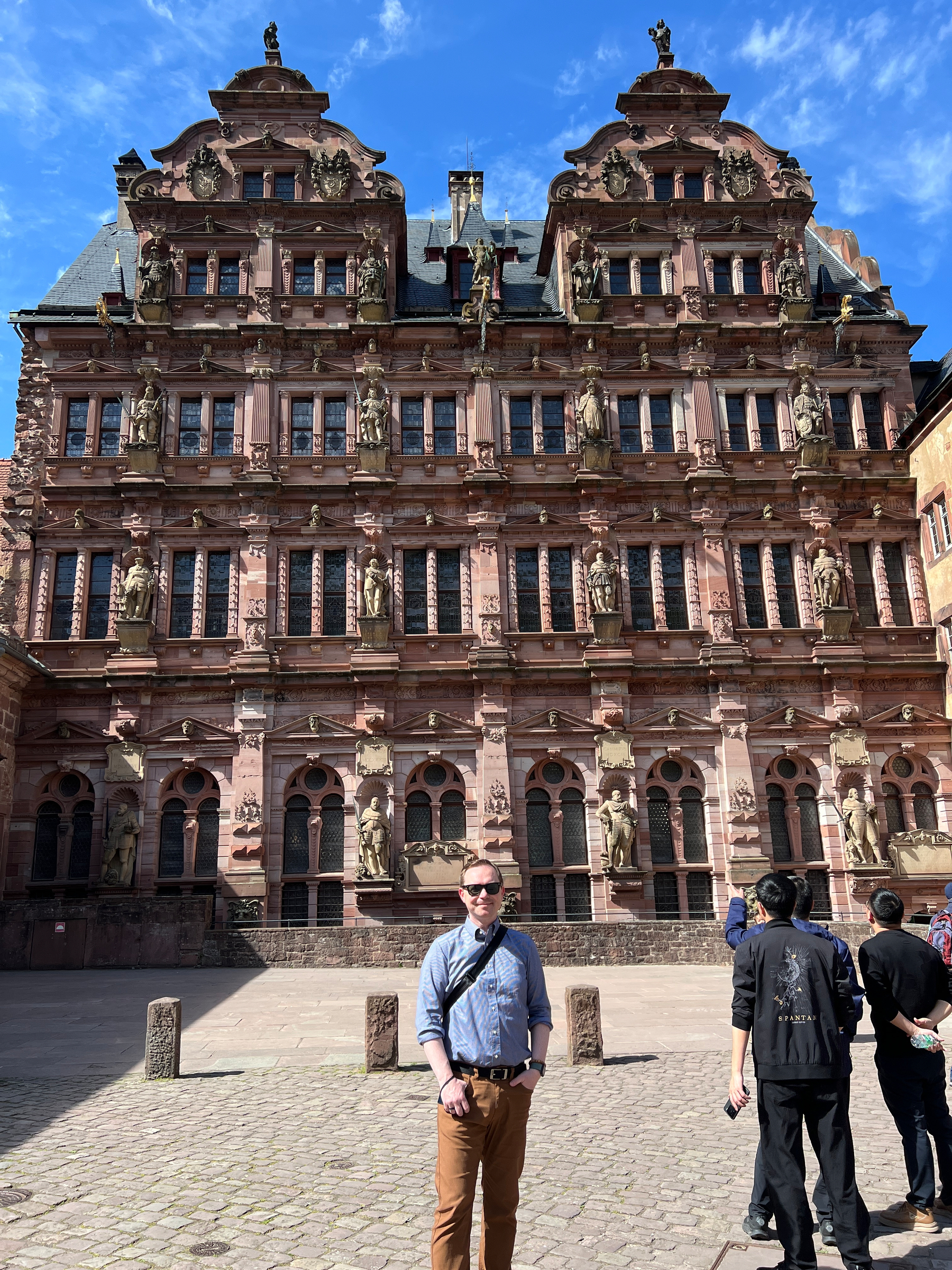 Chad stands in front of the ornate inside wall at Heidelberg castle which is covered with statues of kings