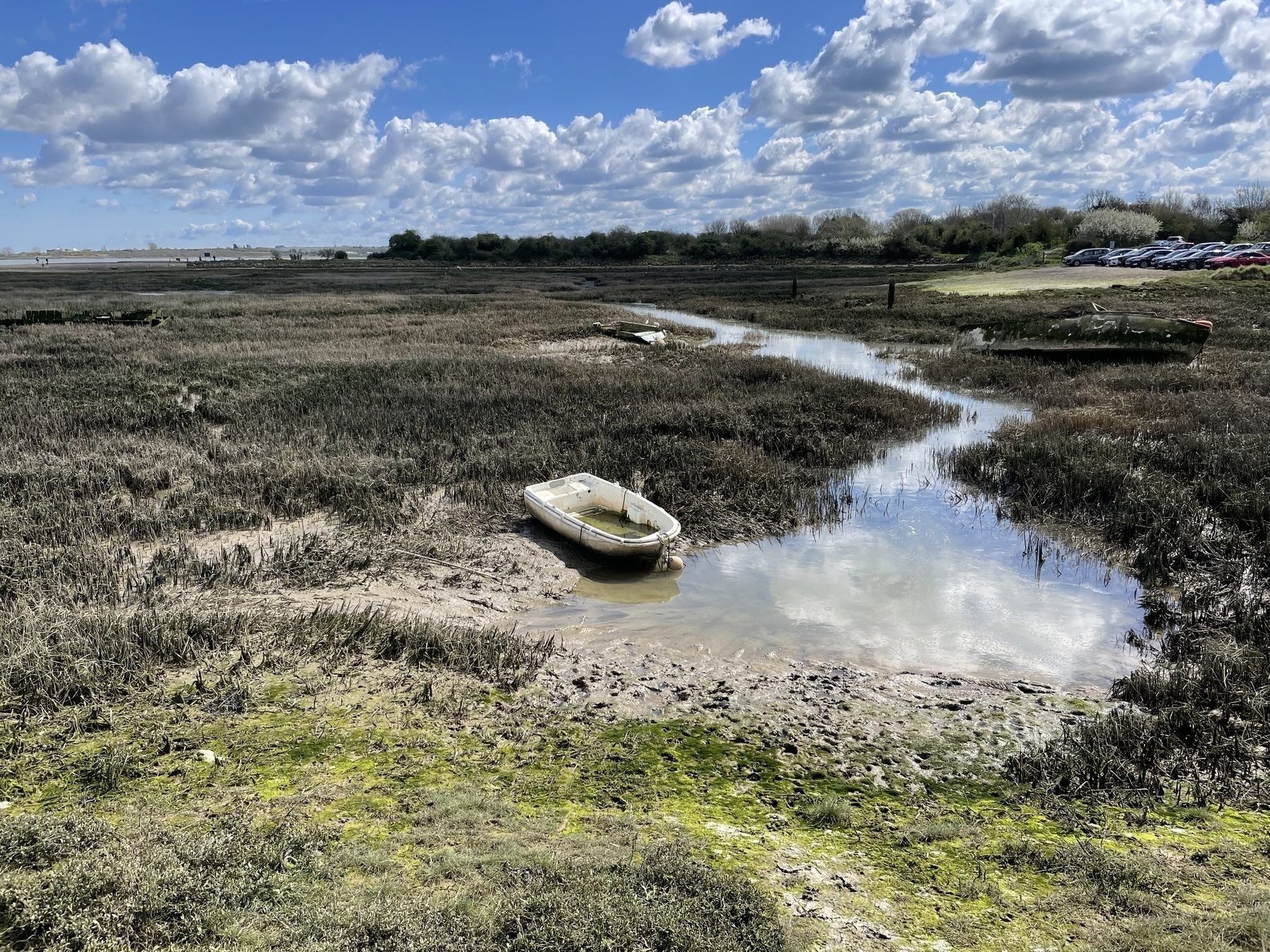 A small boat sits on the bed of a salt marsh at low tide.