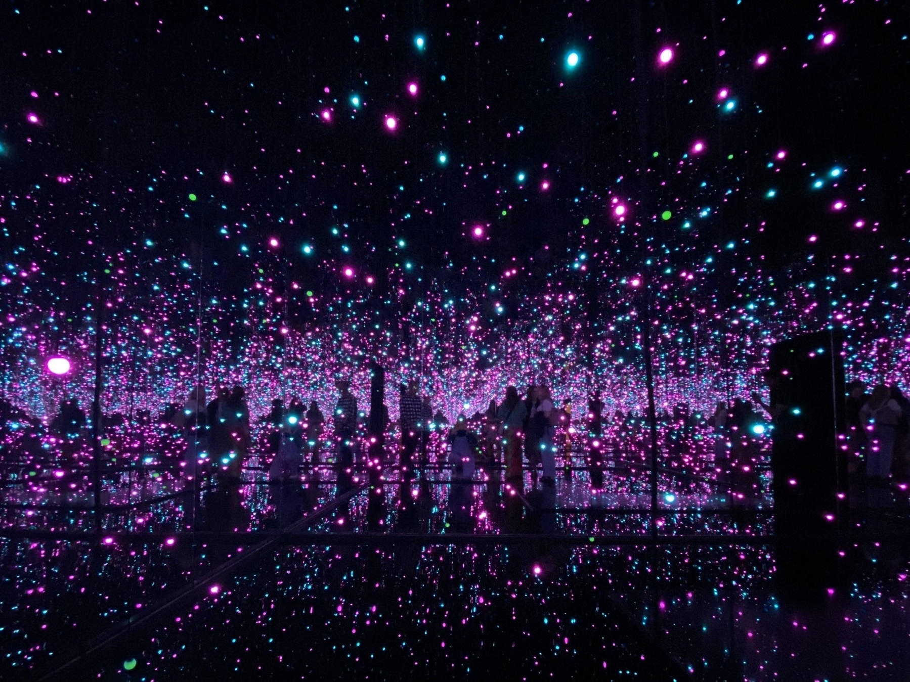 A room full of mirrors and lights of different colours, so that it seems to stretch on forever.