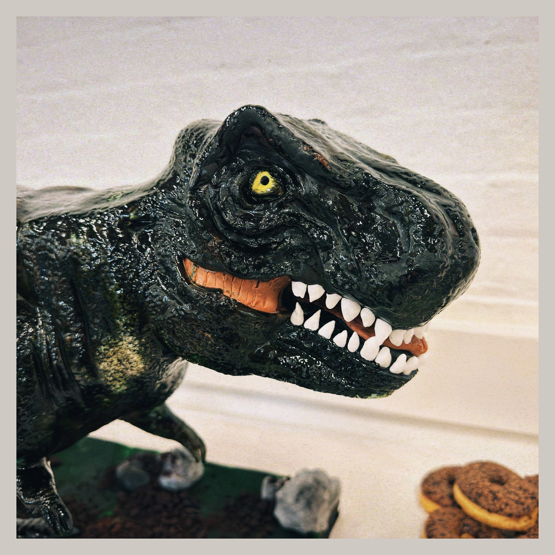 Auto-generated description: A realistic Tyrannosaurus rex model with sharp teeth and bright yellow eyes is positioned near a few round, textured objects.