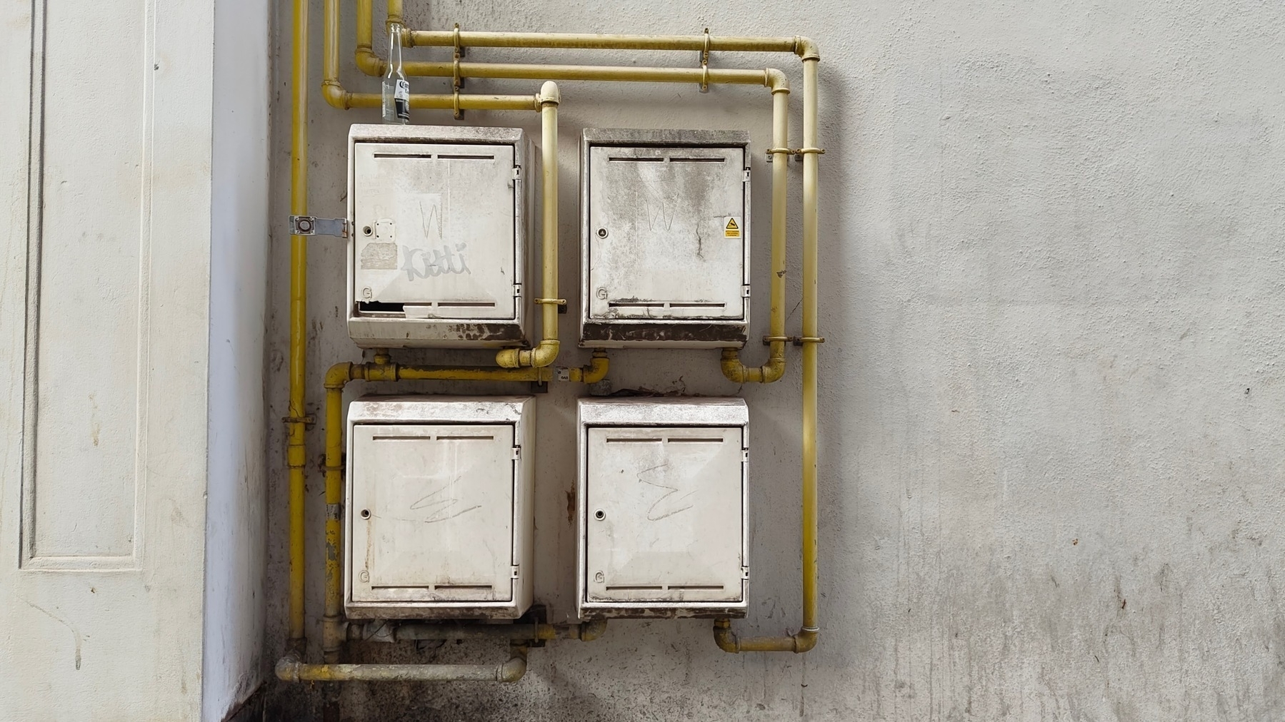 A strangely appealingly geometrical set of pipes and control boxes on a wall