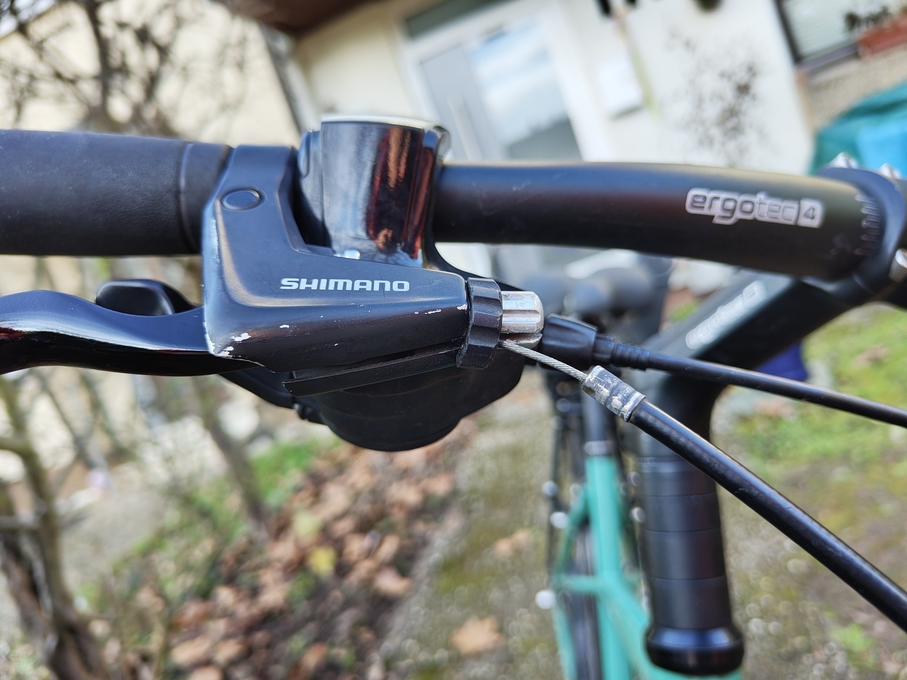 Auto-generated description: A close-up of a bicycle handlebar showing the gear shifter and a brake cable that had been slipped out of its housing.