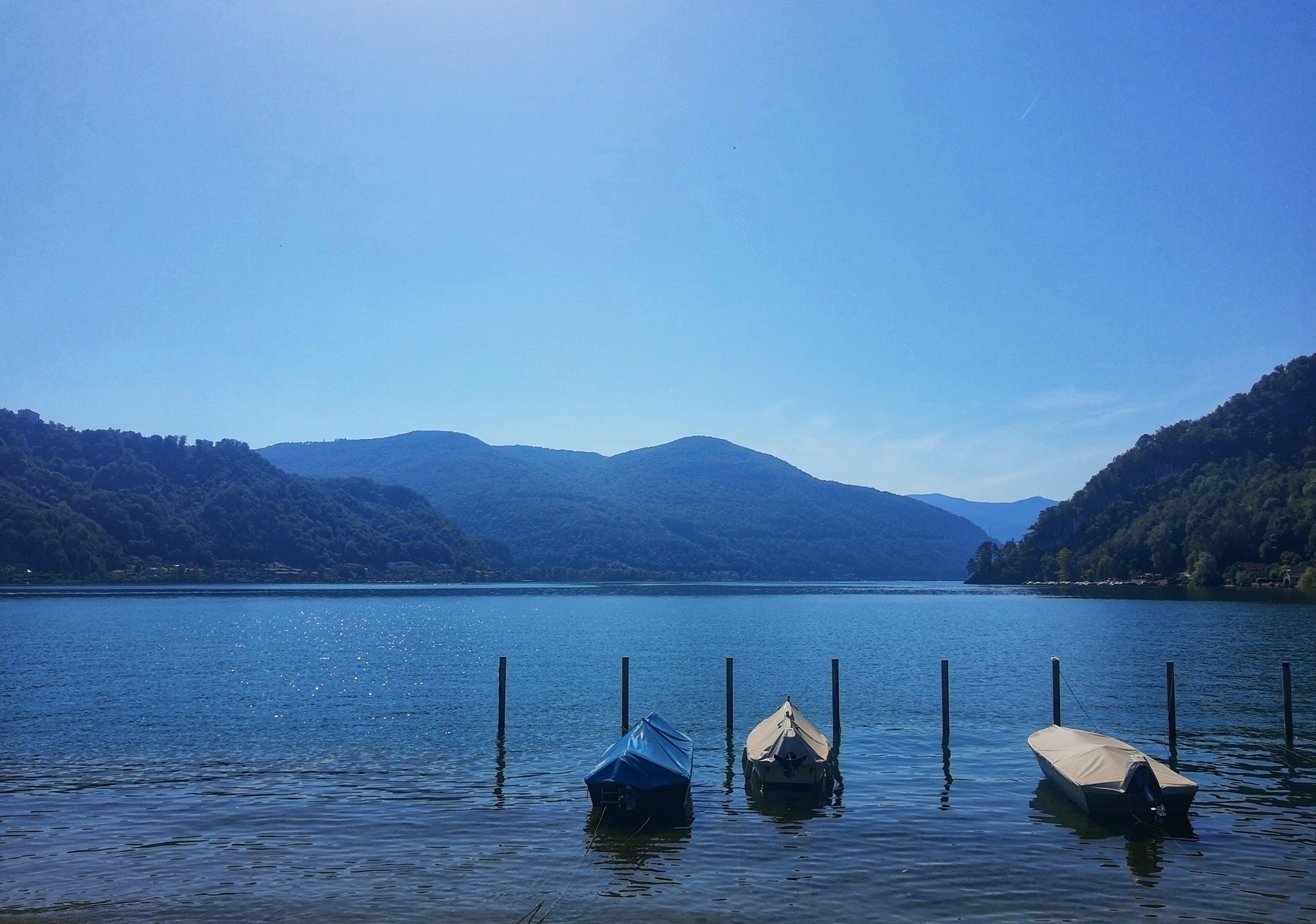 Lago blu con barchette attraccate sotto un cielo azzurro