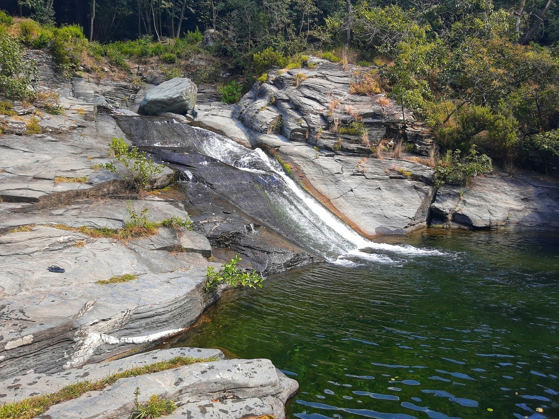 Laghetto nelle alpi liguri formatosi all'interno di rocce con cascatella laterale dalla quale fluisce l'acqua