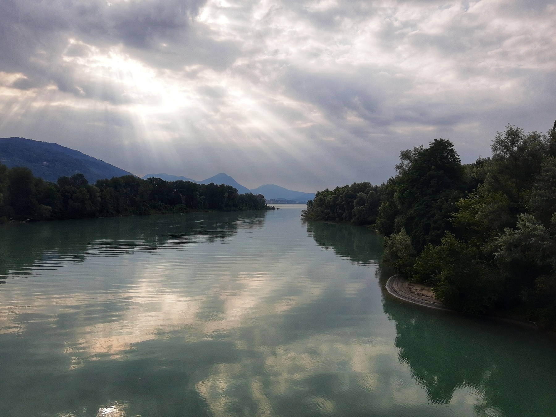 Luce solare che filtrando dal cielo si rispecchia nella foce del fiume