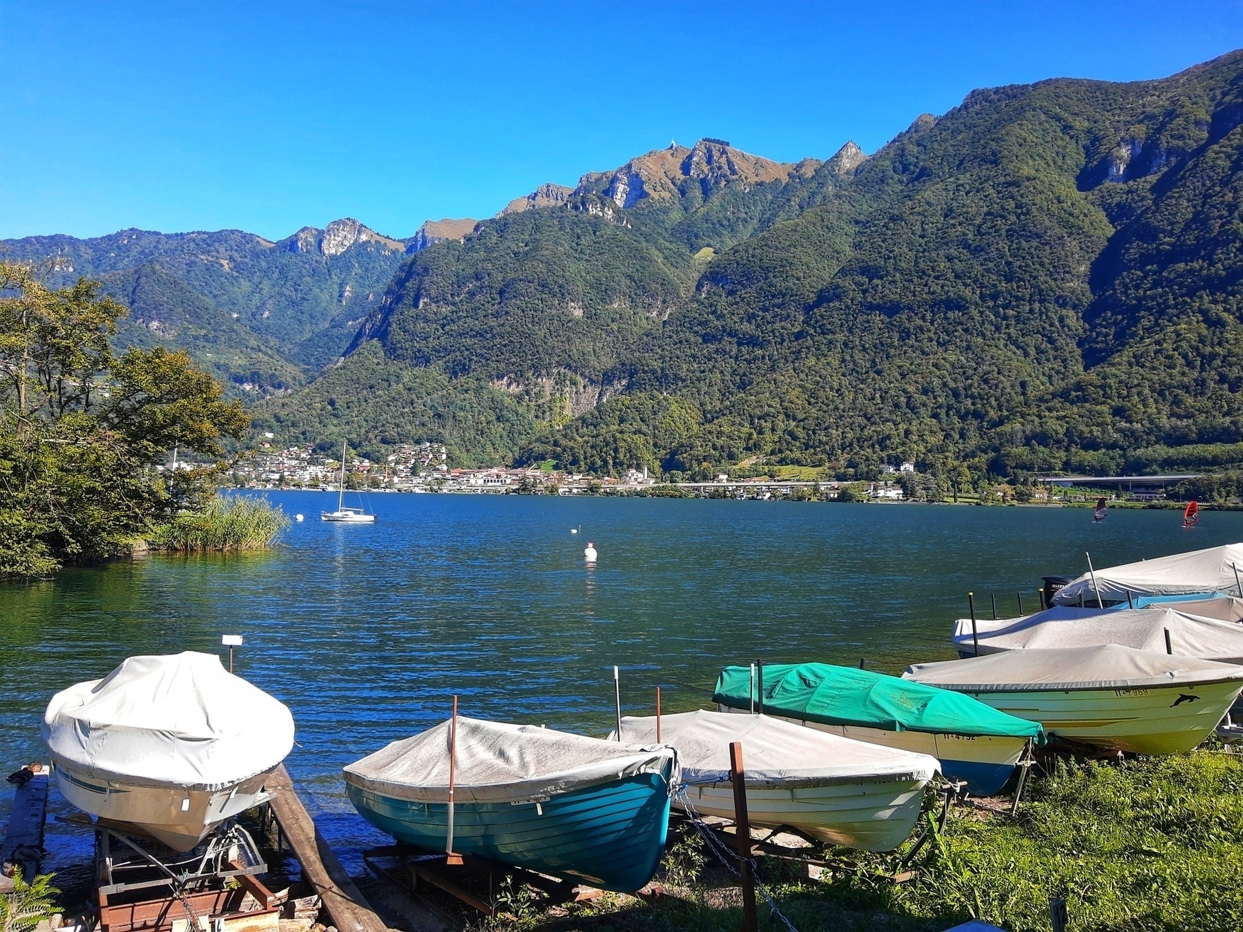 Auto-generated description: A serene lake is surrounded by mountains, with boats docked along the shore.