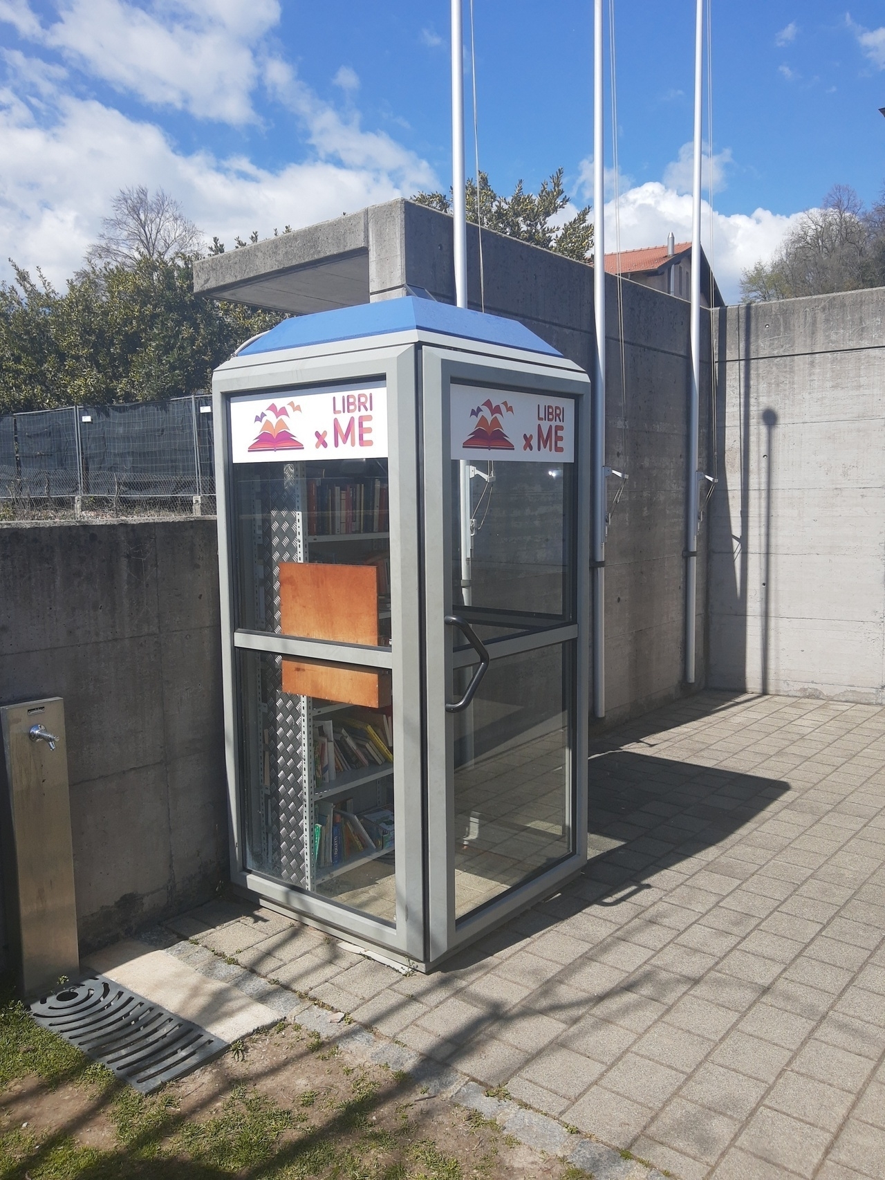 Auto-generated description: A phone booth has been repurposed into a small public library with bookshelves inside.