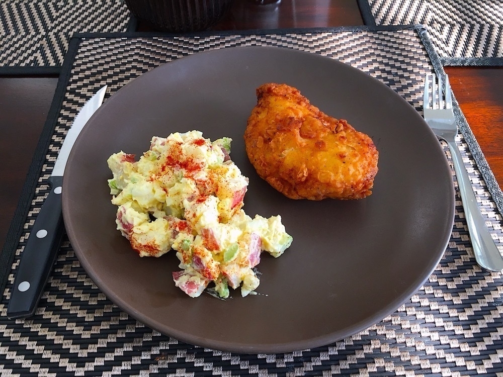 Crispy fried chicken and potato salad on a plate.