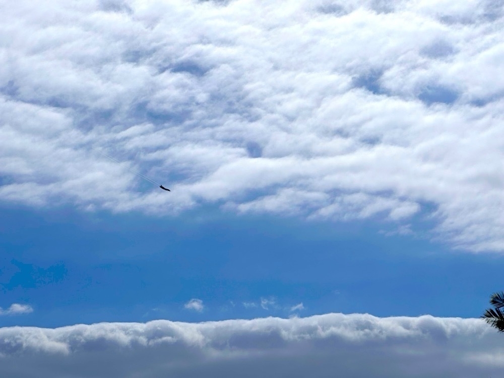 A fighter jet against clouds in the sky.