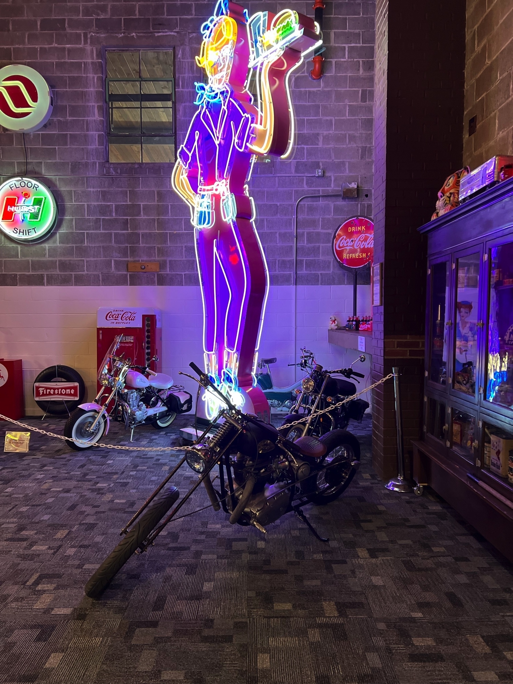 A vintage-style room features neon signs, a classic motorcycle, and a collection of nostalgic memorabilia.