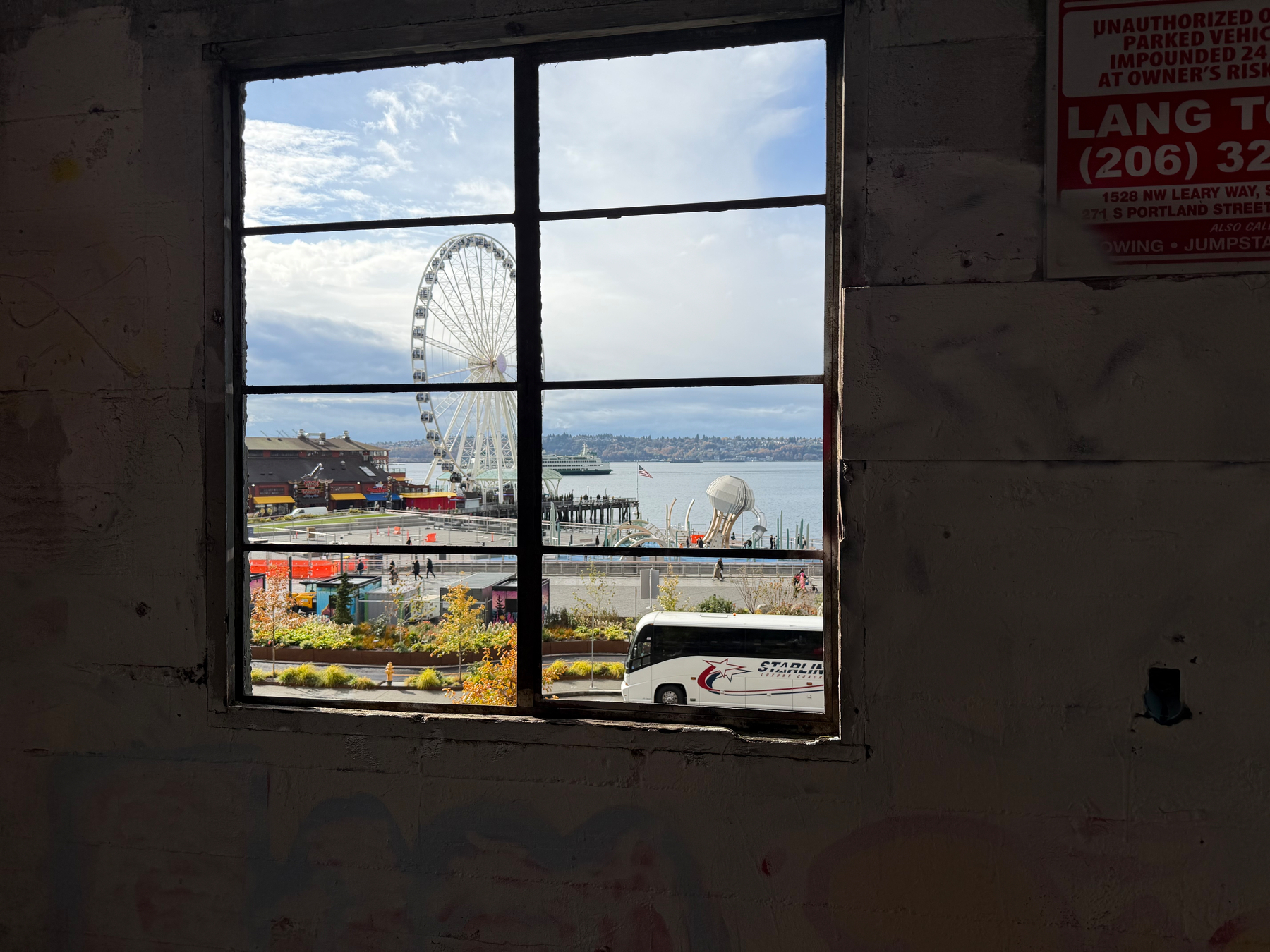 A ferris wheel and waterfront view are framed by a window from inside a building.