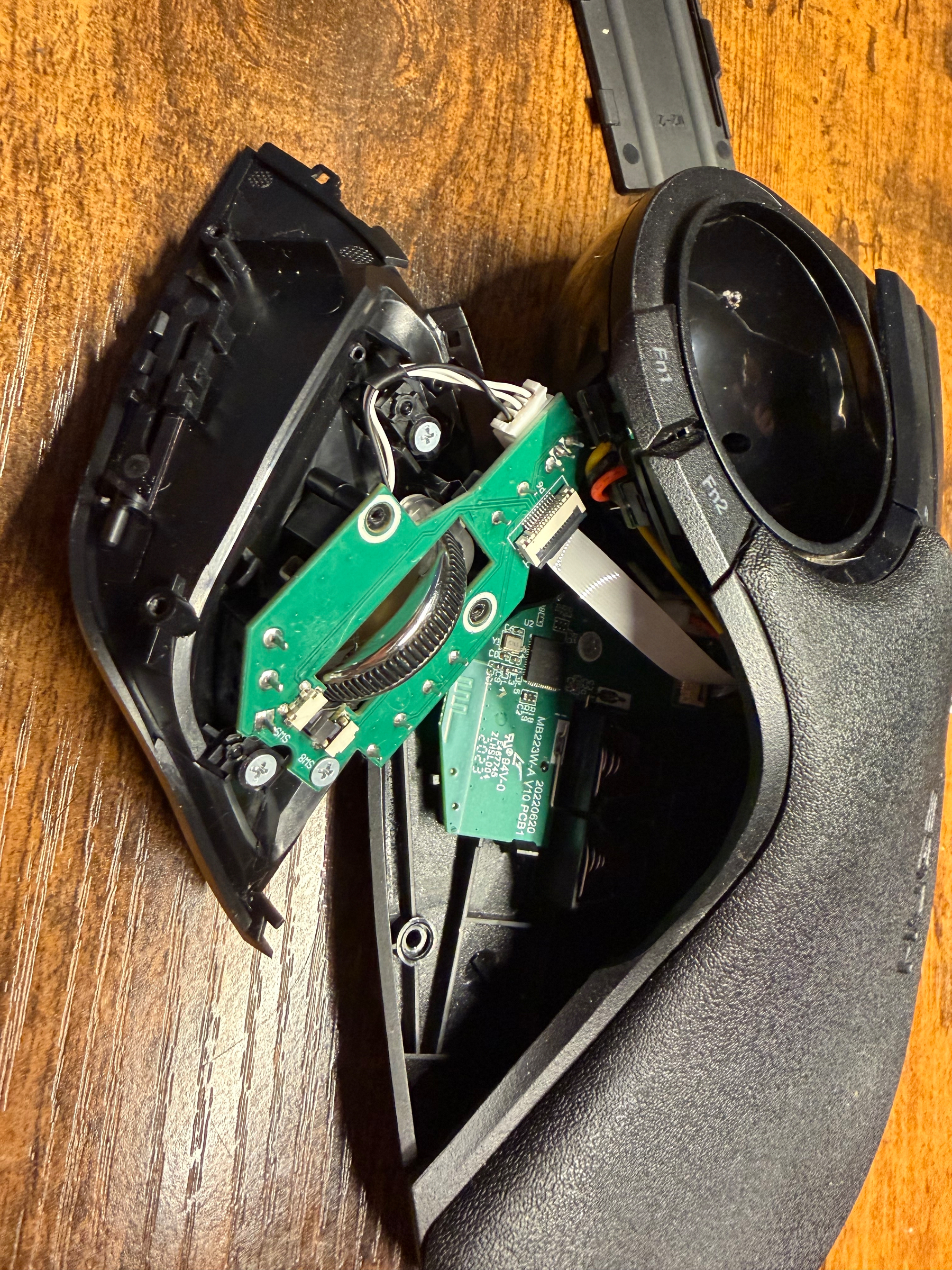 A disassembled Elecom HUGE marble mouse is resting on a wooden surface with visible circuit boards inside.