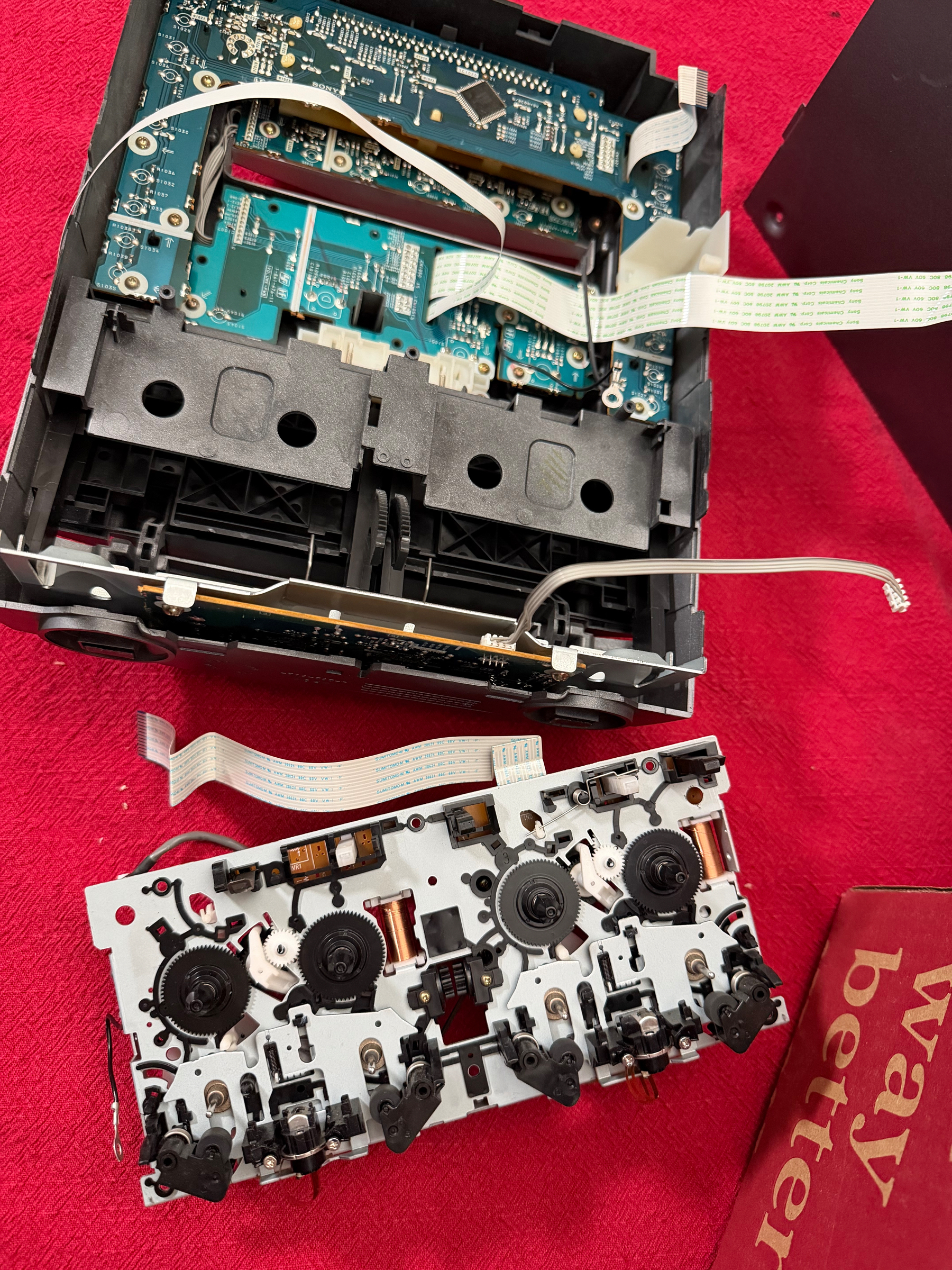 An open electronic device with visible circuit boards and components is placed on a red surface.
