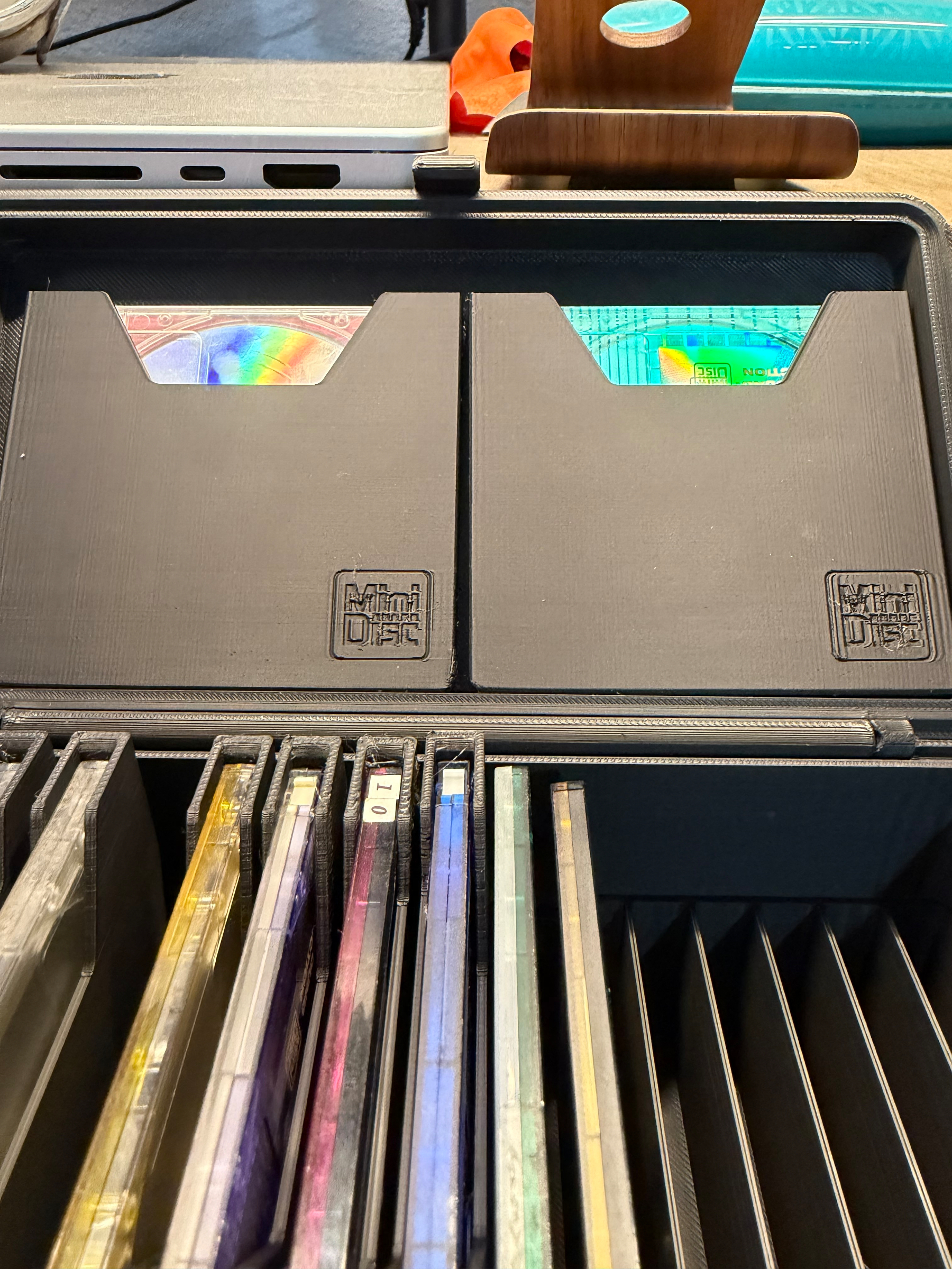 A collection of MiniDiscs and two MiniDiscs cases are organized inside a storage container.