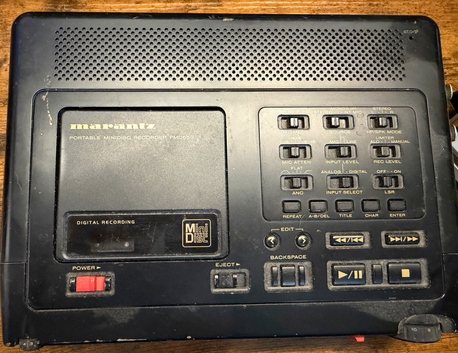 A black Marantz portable Minidisc recorder PMD530 with various control buttons and switches is shown on a wooden surface.