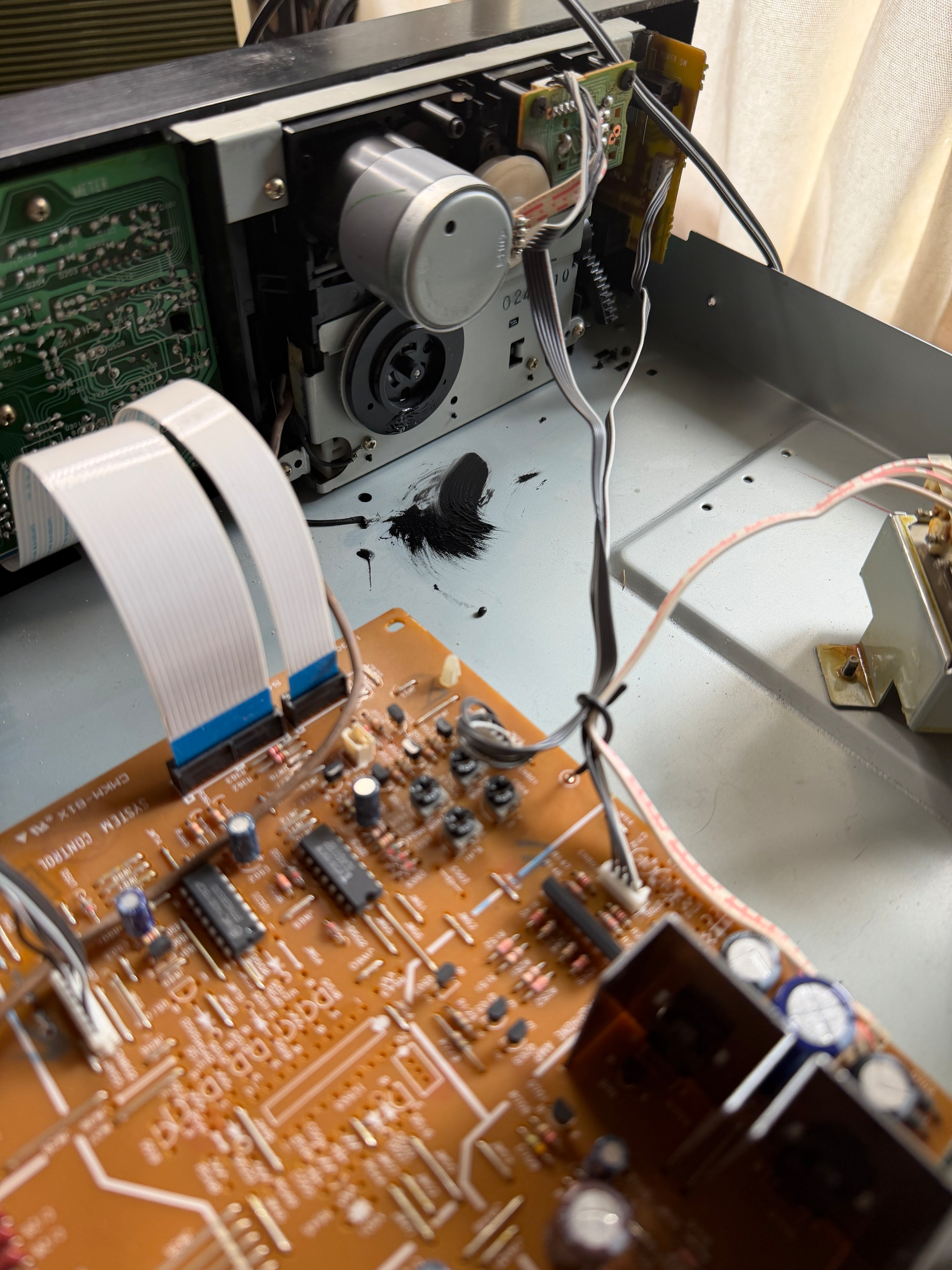 With the top off of Sony TC-W345 reveals internal circuit boards, a motorized component, and a black stain on the metal surface. That’s the belt y’all, turned to goo!
