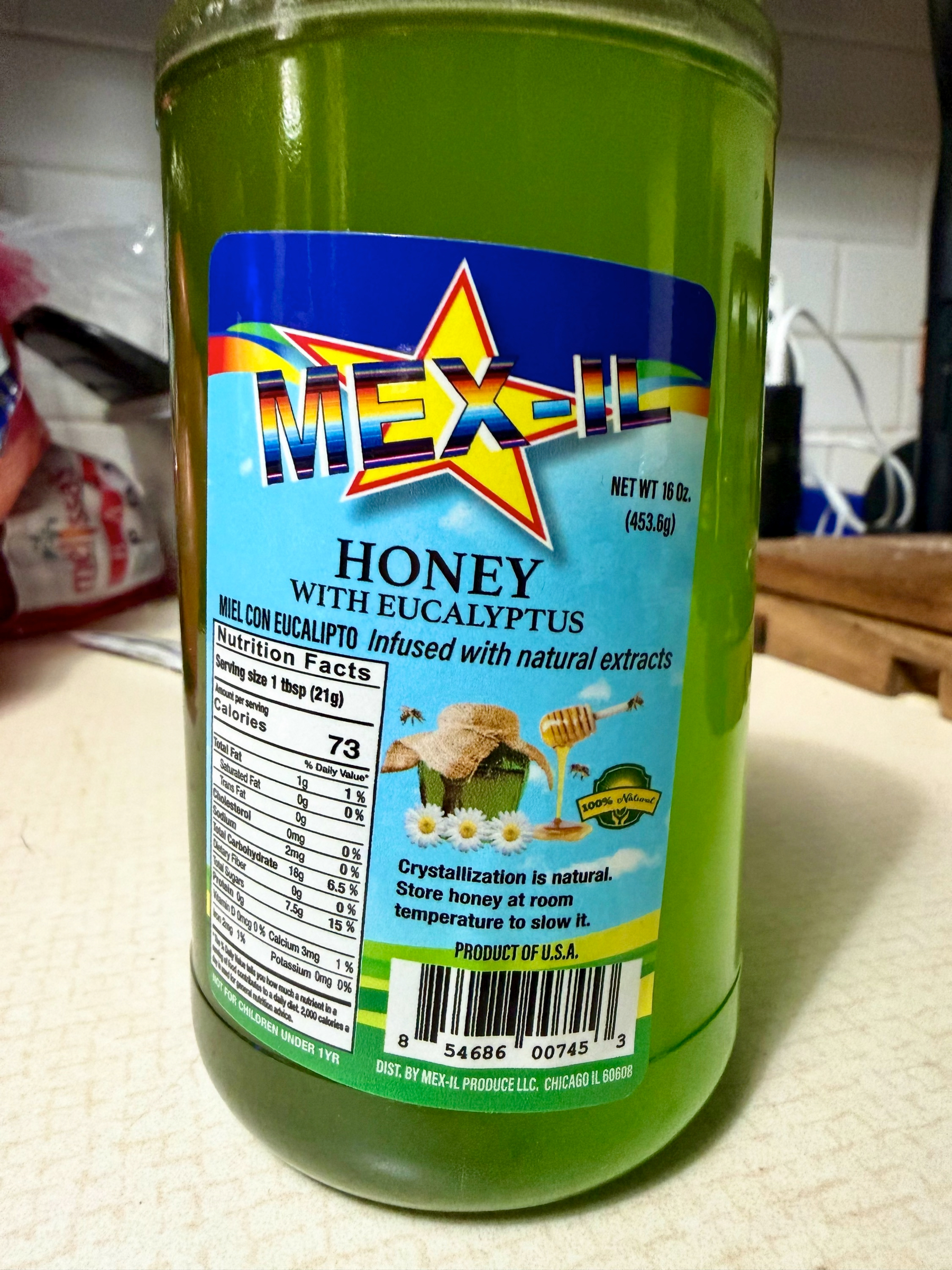 A jar of Mex-il honey with eucalyptus, labeled as infused with natural extracts and containing nutritional information, is placed on a kitchen countertop.