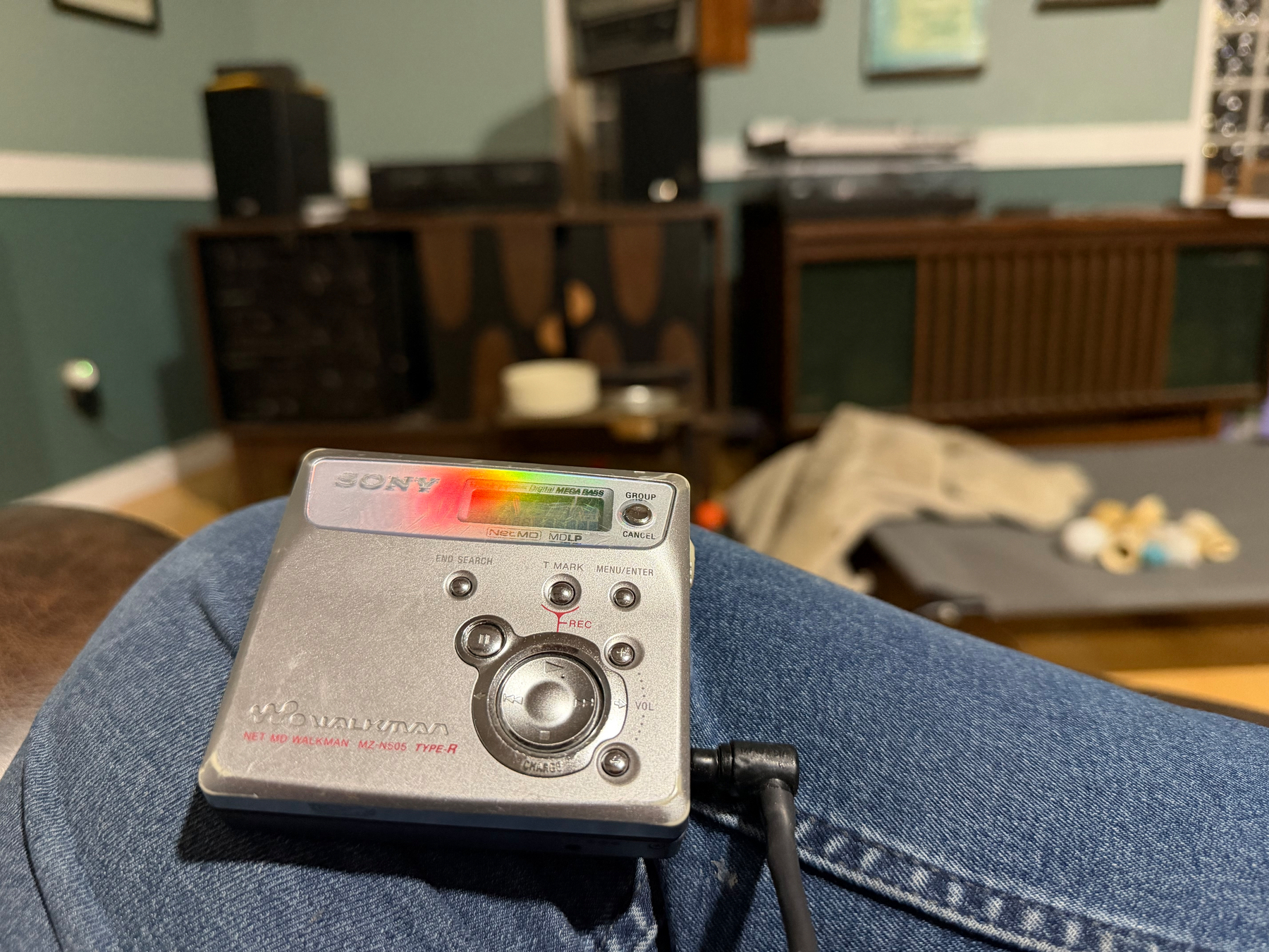 A portable Sony MiniDisc MZ-505 player is resting on my knee, with a stereo cabinets and a dog bed in the out of focus background.