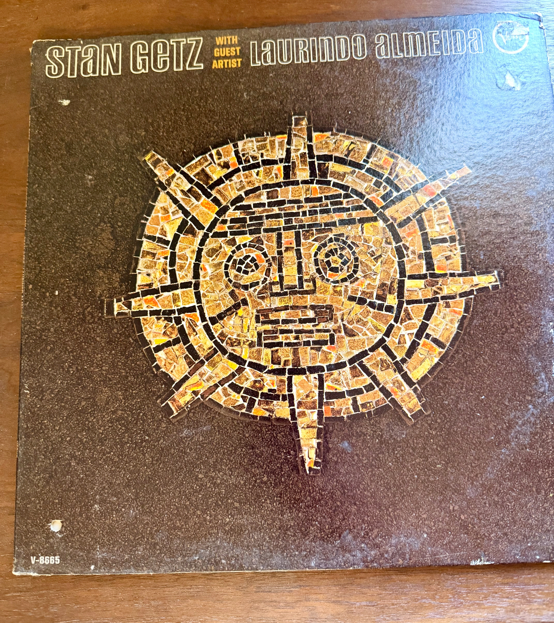 A vinyl record cover features an abstract mosaic sun face design with the names Stan Getz and Laurindo Almeida prominently displayed.